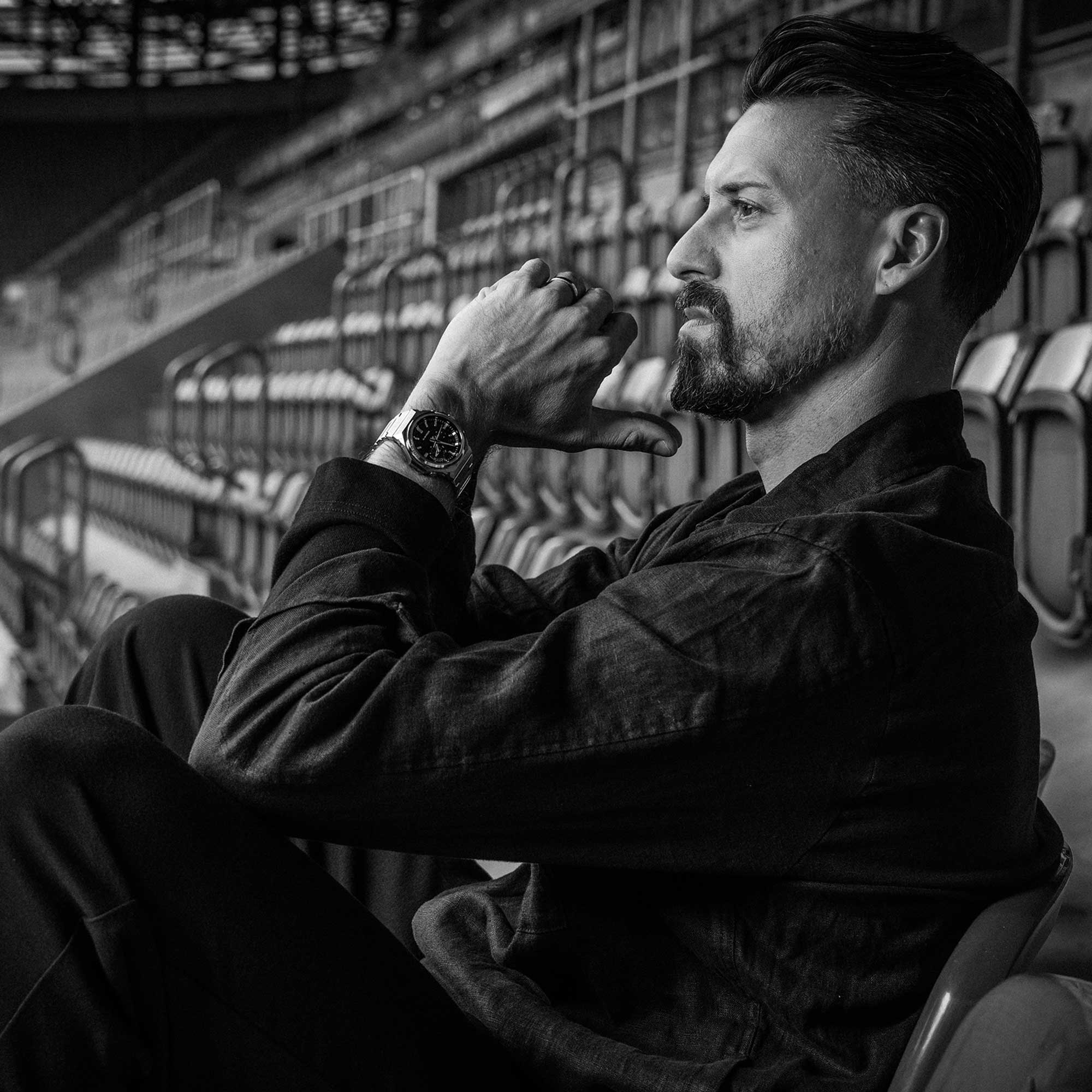 Sandro Wagner sitzt auf einer Tribüne und trägt die GST-B1000-1AER am Handgelenk. L