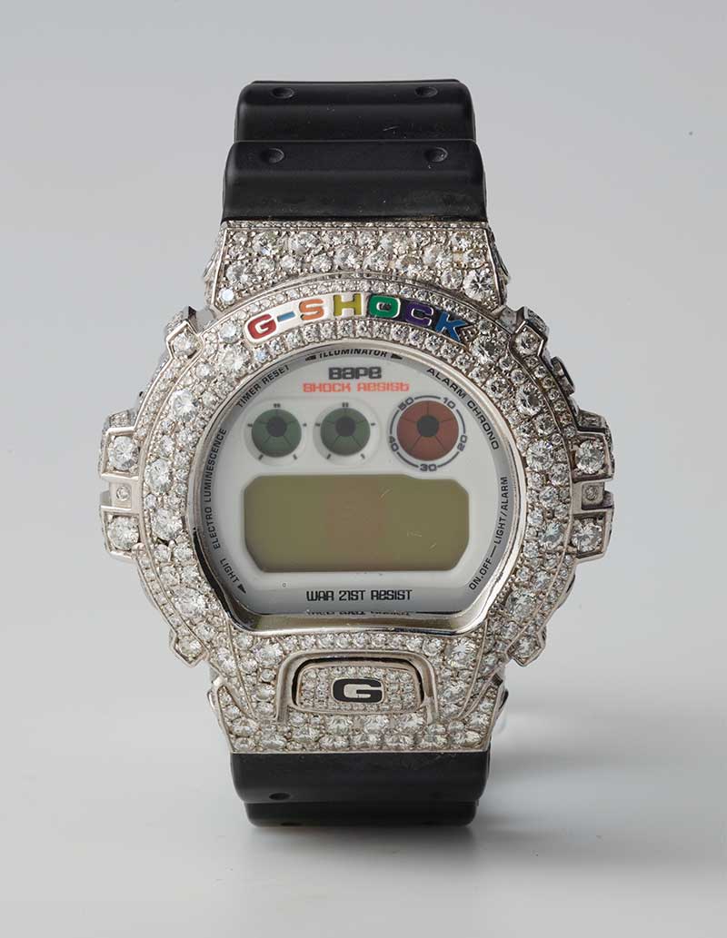 Nahaufnahme einer digitalen Armbanduhr von G-SHOCK in Kollaboration mit BAPE, das Gehäuse ist vollständig mit Strasssteinen besetzt.