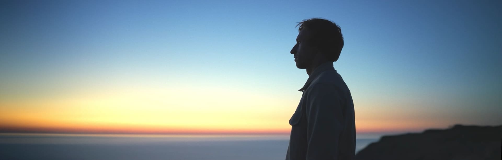 Eine Person vorm Sonnenuntergang am Meer