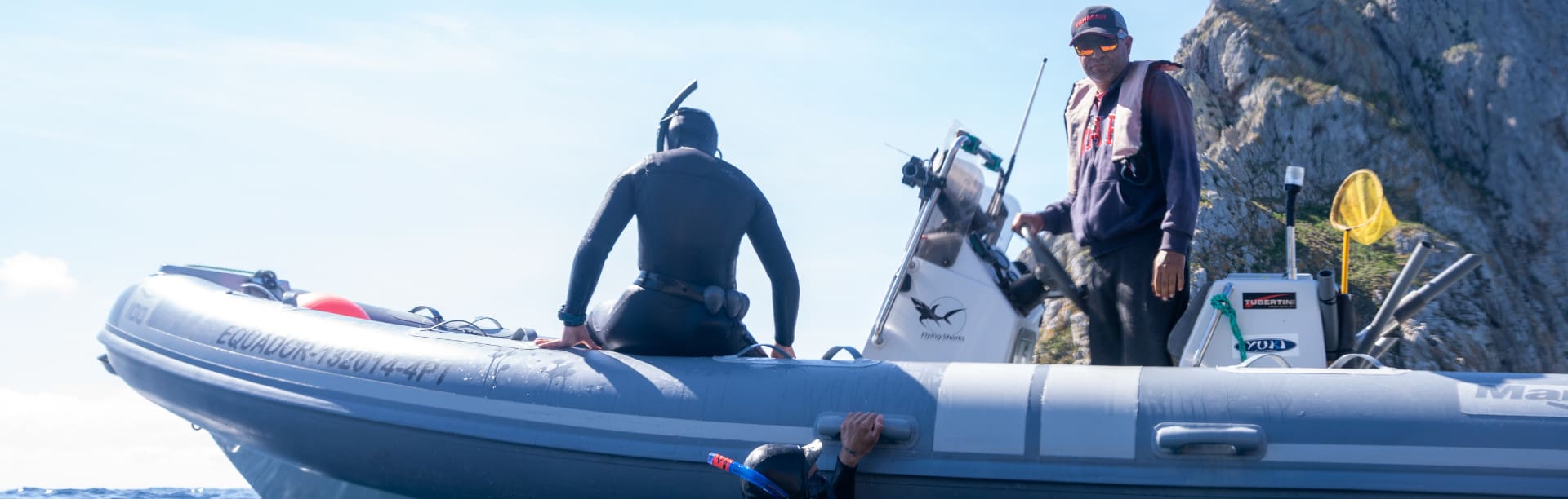 Lena Kemna im Neonprenanzug und mit Schnorchel sitzt in einem Schlauchboot und bereitet sich aufs Freediven vor.