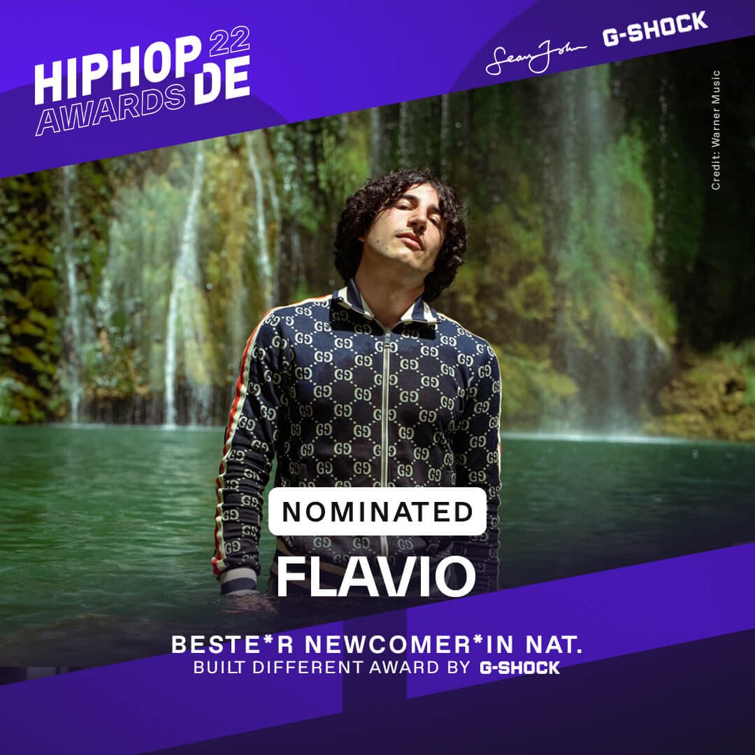 Rapper Flavio steht in blauem Tracksuit vor einem Wasserfall und war als bester Newcomer national nominiert