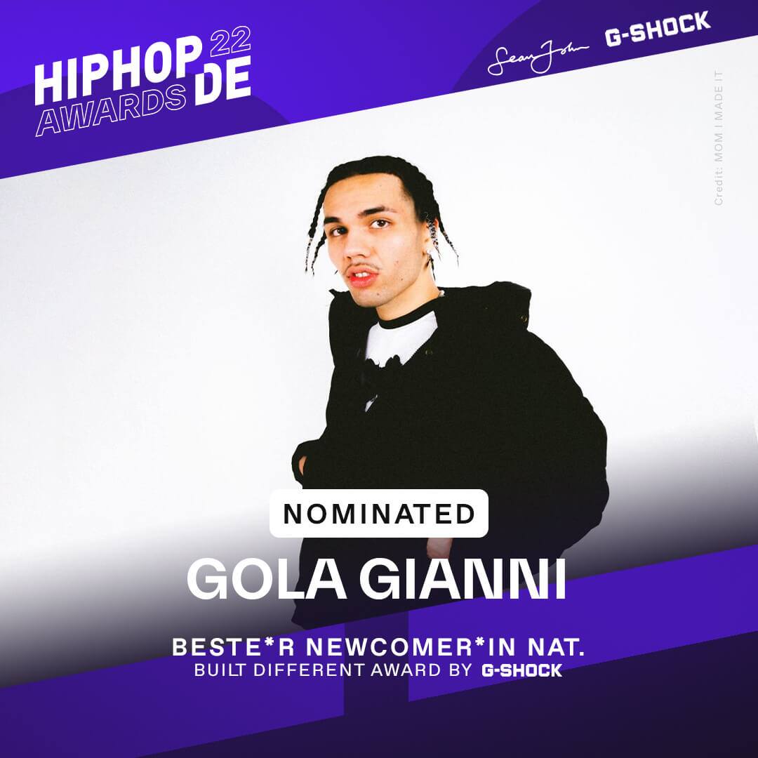 Rapper Gola Gianni steht in schwarzem Hoodie vor einer weißen Wand und war als bester Newcomer national nominiert