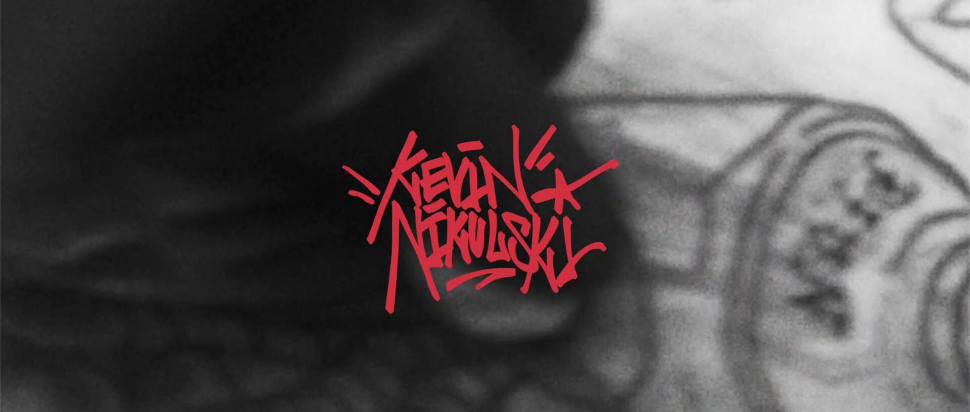 Ein Graffitischriftzug "Kevin Nikulski" über dem Tattoo einer Person