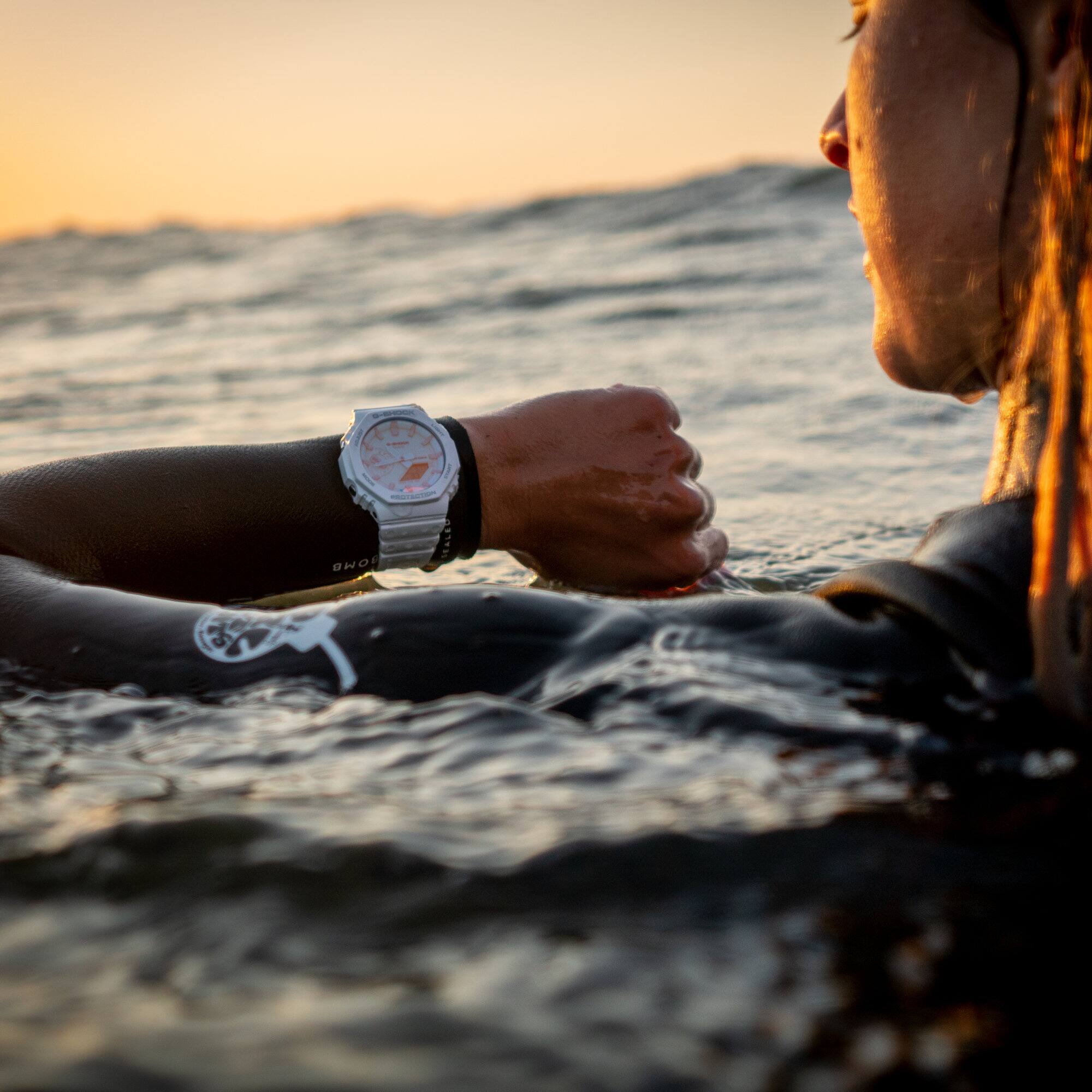 Eine Frau im Neoprenanzug im Wasser schaut auf die GA-2100TL-7A an ihrem Handgelenk.
