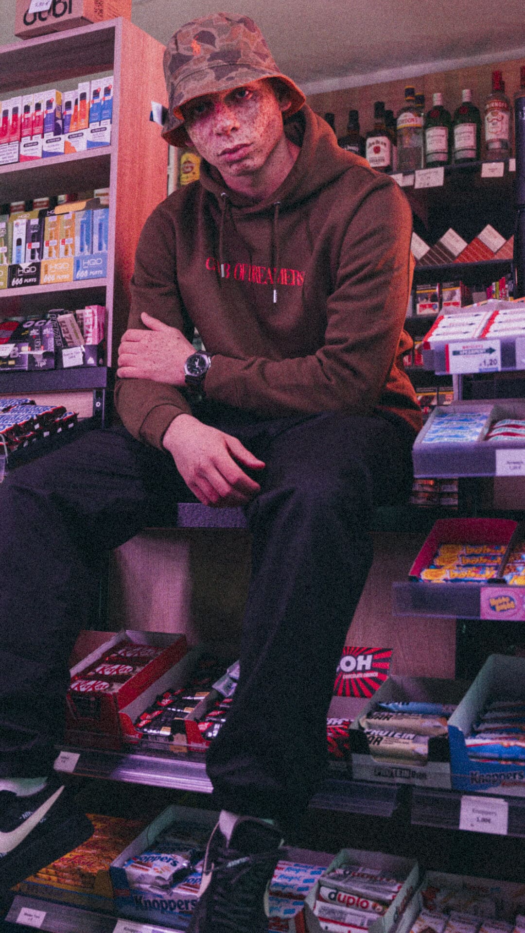 Ein Mann sitzt auf einem Kiosktresen, am Handgelenk trägt er die G-SHOCK Uhr mit Stoffarmband