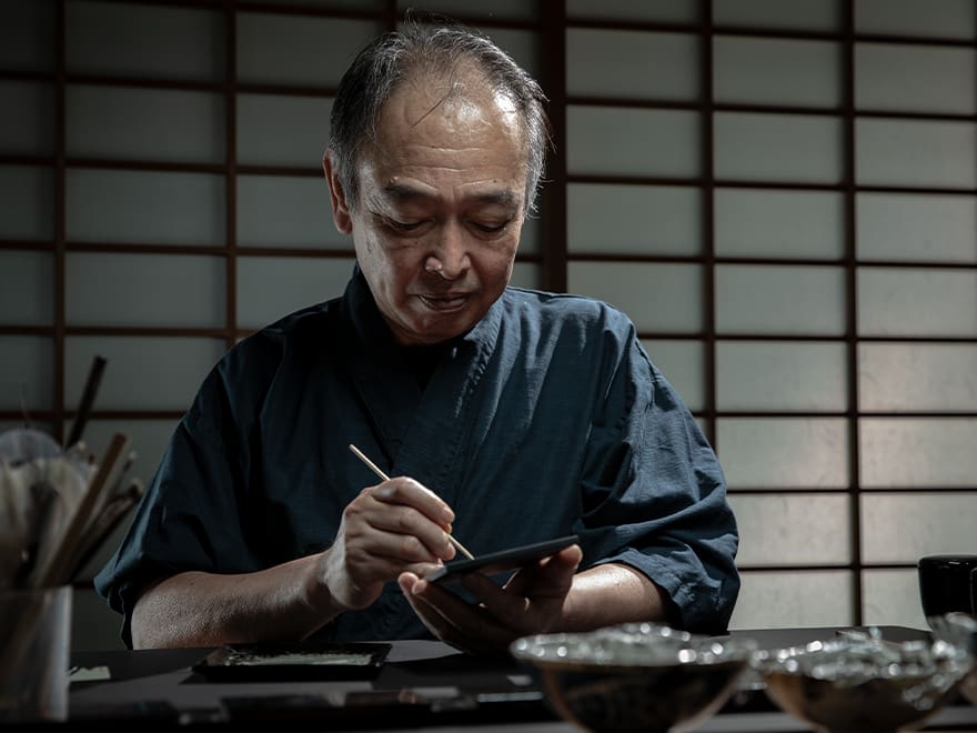 Portrait des traditionellen Kunsthandwerkers Nomura Mamoru bei der Arbeit
