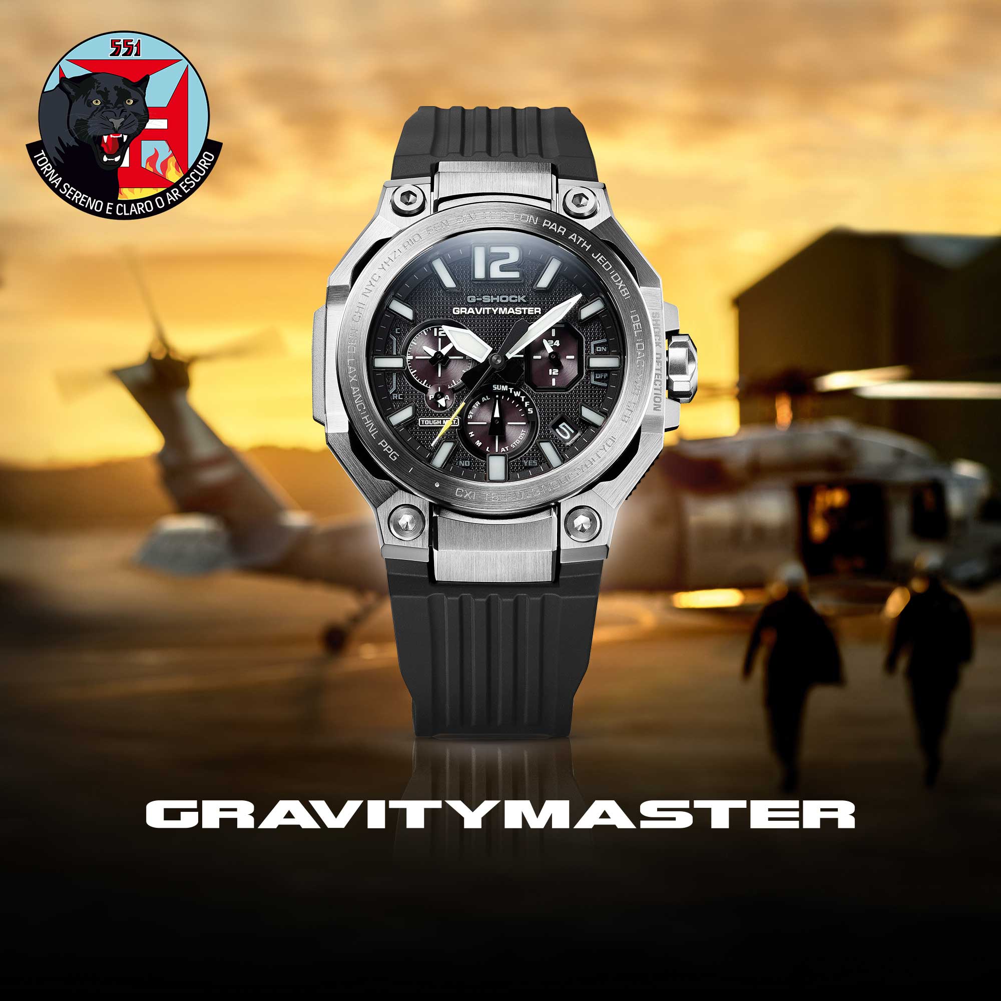 Die G-SHOCK Gravitymaster Armbanduhr mit silbernem Gehäuse und schwarzen Armband, im Hintergrund ist ein Helikopter bei Sonnenuntergang auf einem Landeplatz zu sehen. Link zur Landingpage der Armbanduhr.