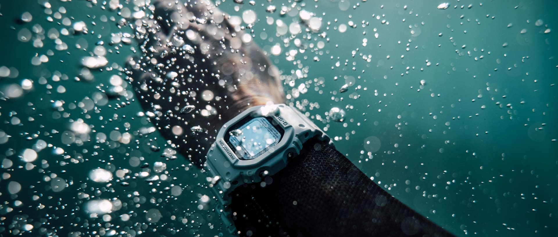 Die G-SHOCK GW-5000HS-7ER am Handgelenk unter Wasser, umgeben von kleinen und großen Luftblasen
