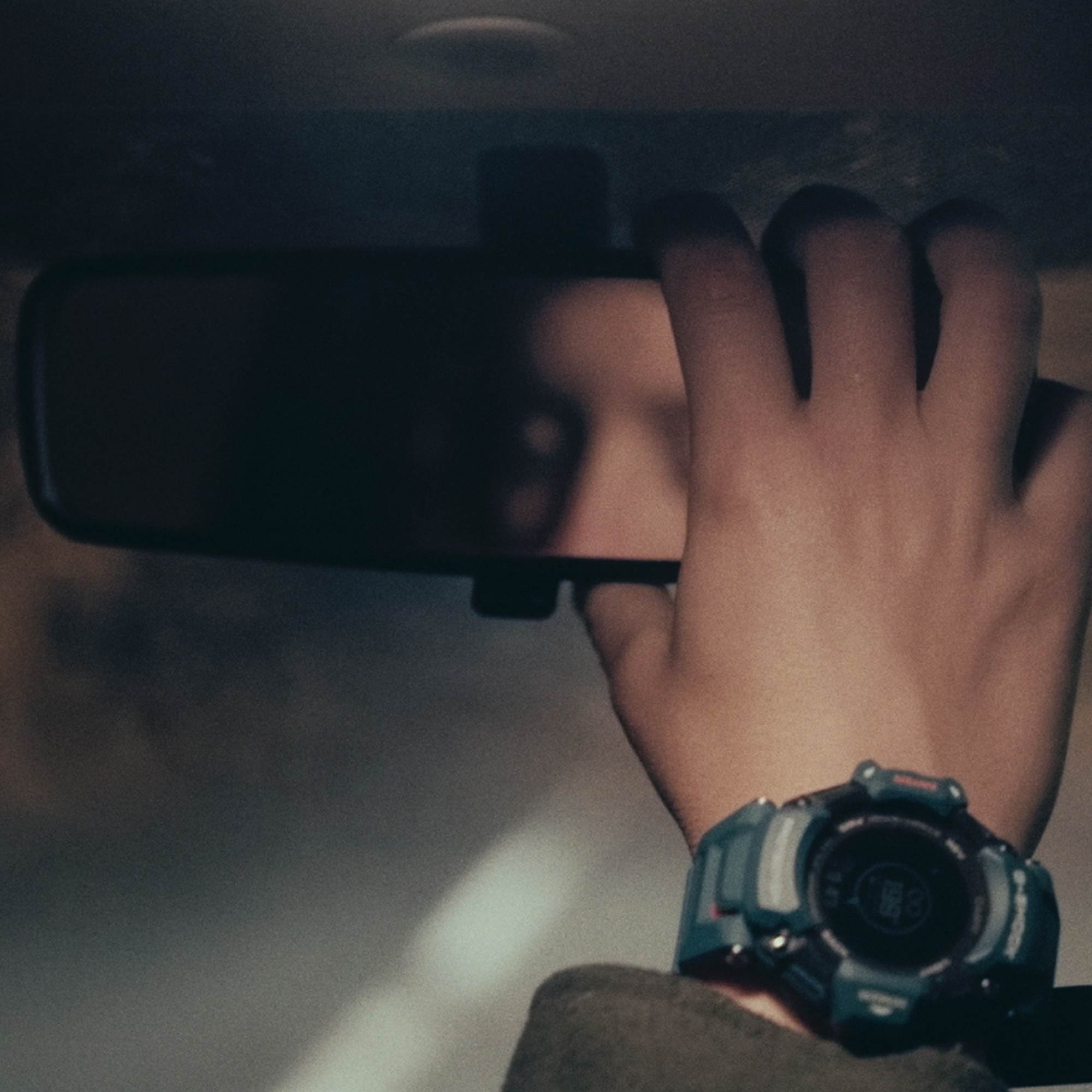 An einem Handgelenk ist die G-SHOCK GBD-H2000 zu sehen, die Hand greift nach dem Rückspiegel im Auto