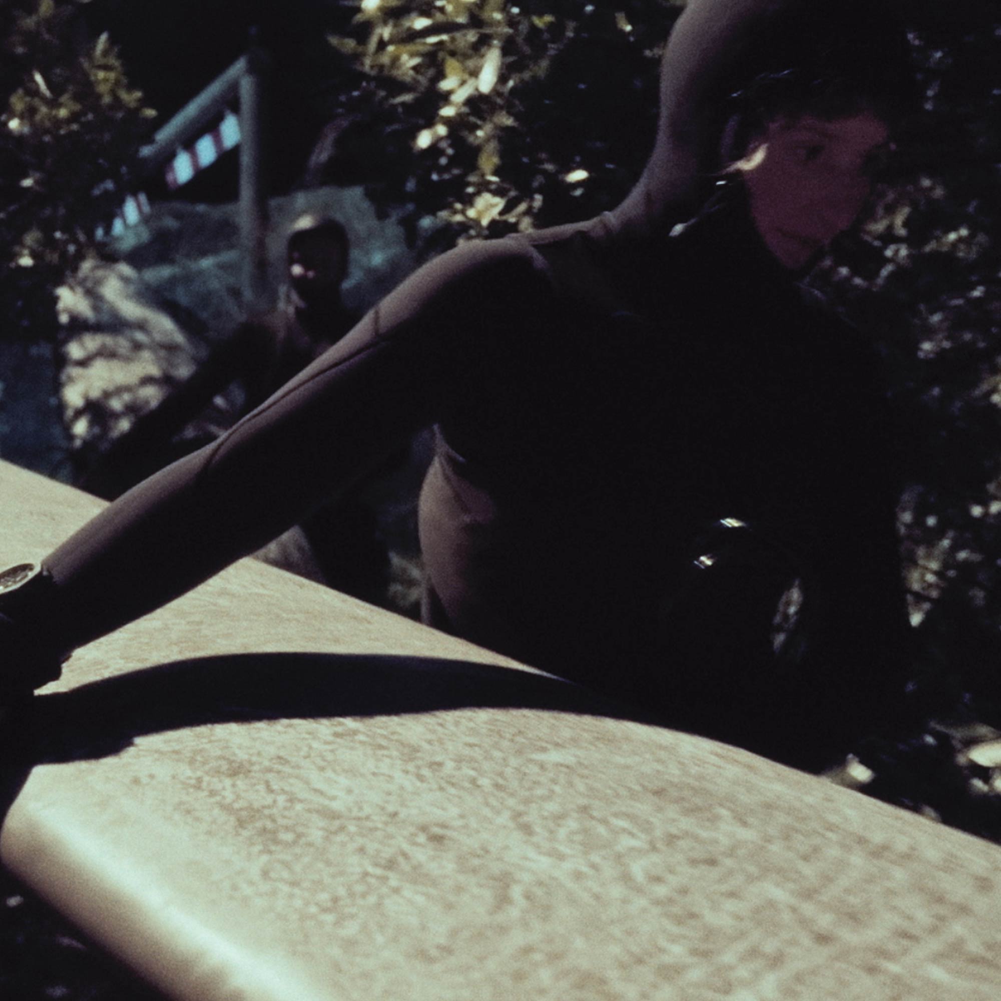 Eine Frau im Dunkeln mit Surfboard unterm Arm