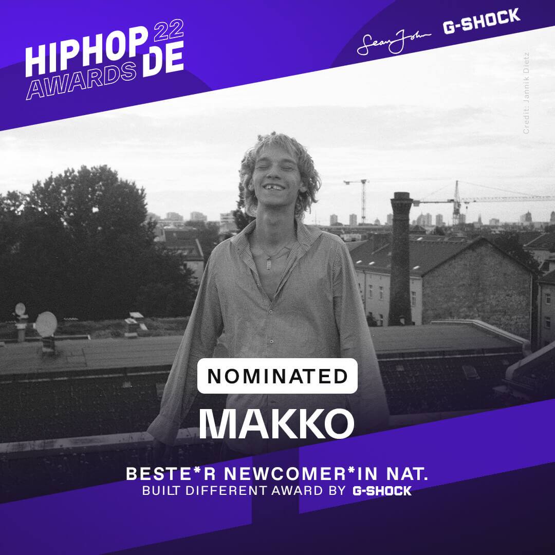 Künstler Makko grinst in einem gestreiften Hemd auf einer Dachterasse in die Kamera, er war als bester Newcomer national nominiert