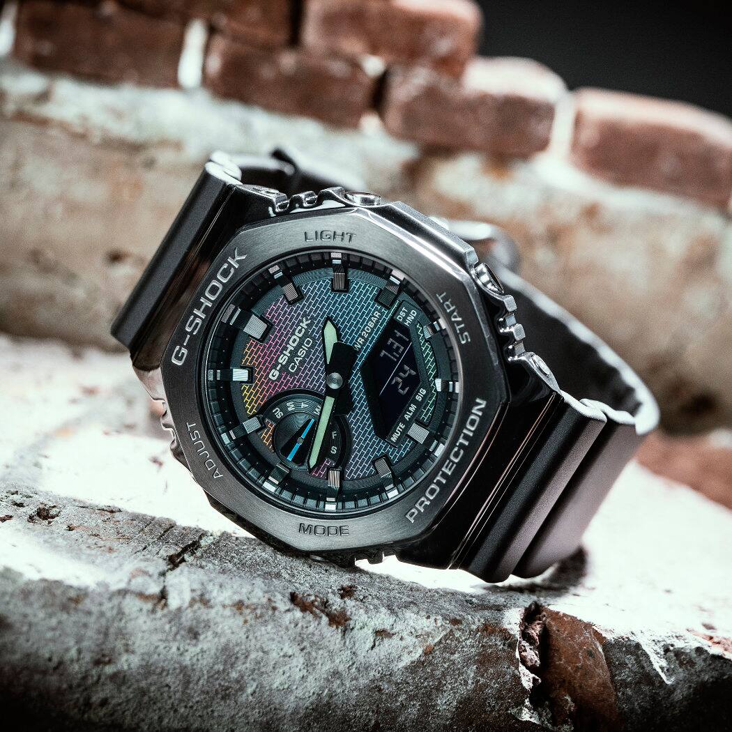 Die Metallband-Analoguhr "GM-2100BRW-1AER" von G-SHOCK auf einer Backsteinmauer