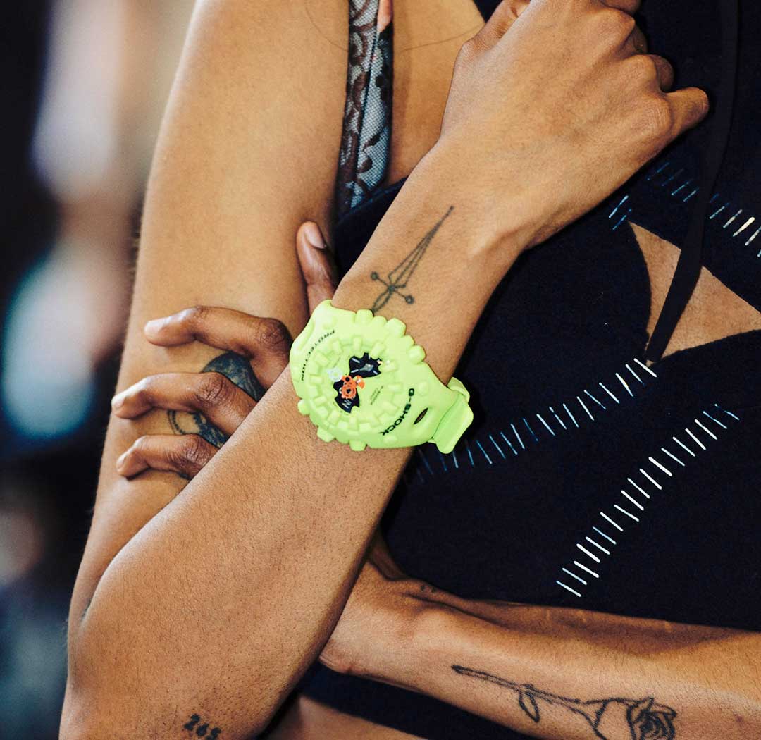 Die neongelbe GA-V01 Armbanduhr am Handgelenk einer tätowierten Frau