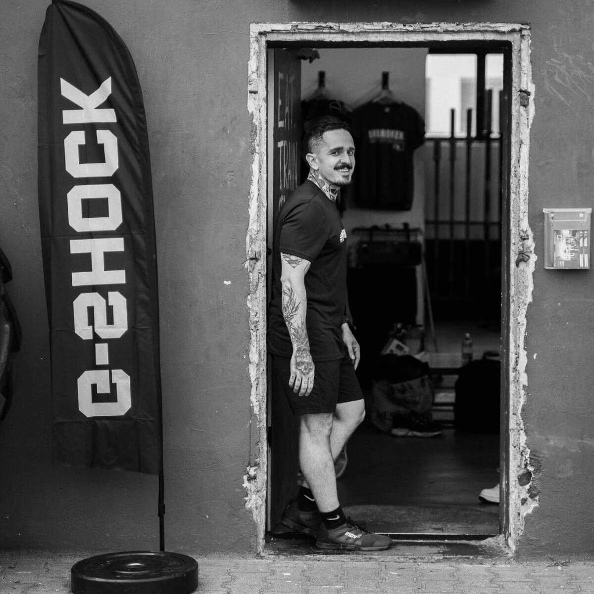 El entrenador de Crossfit Kevin se apoya en el marco de la puerta de su gimnasio.