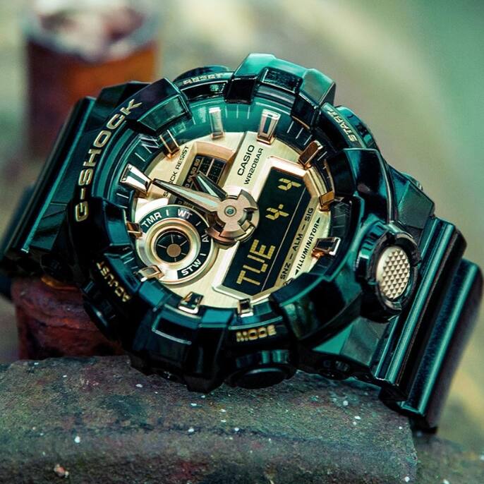 Primer plano del reloj GA-710GB-1ALTD con correa negra brillante y pantalla analógica dorada