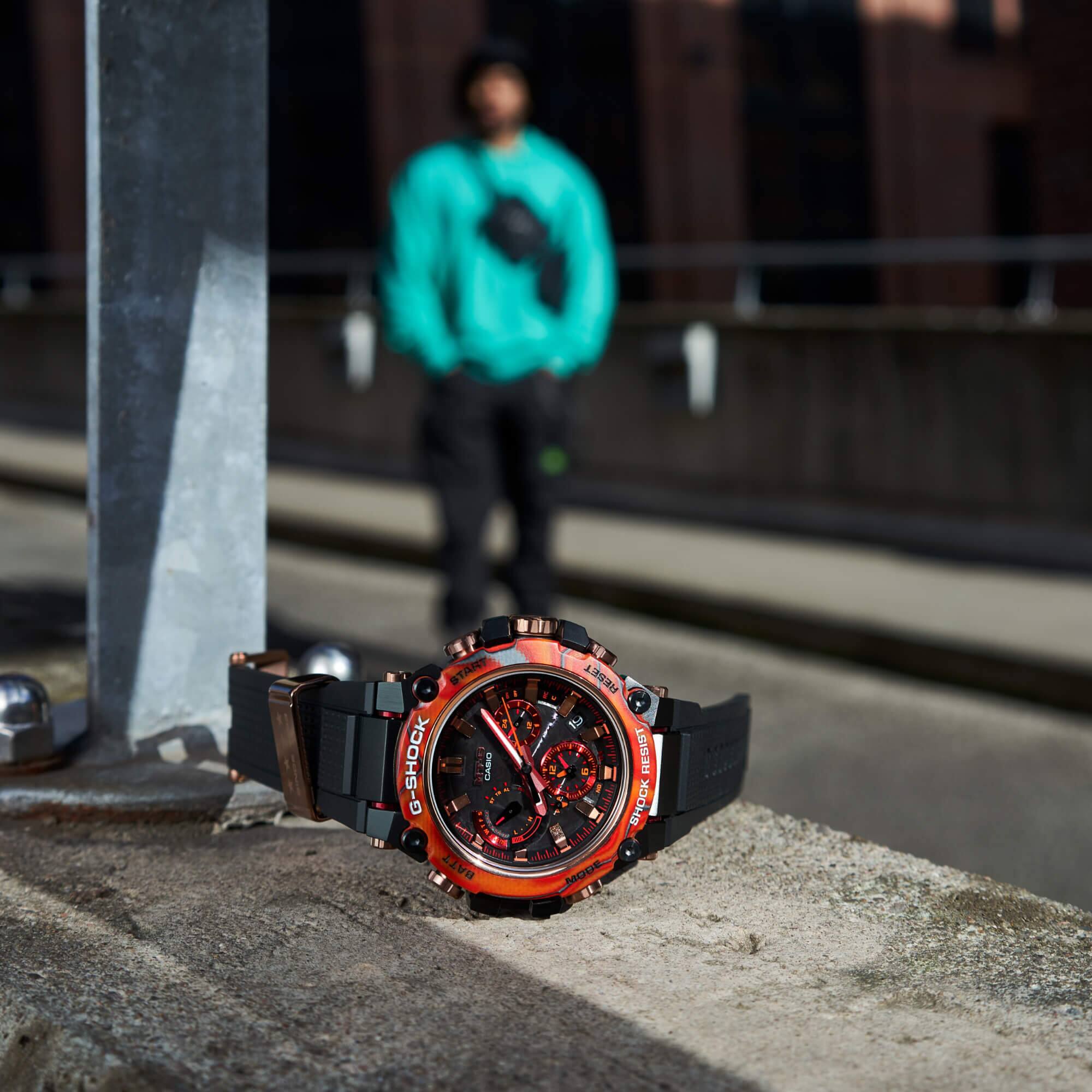 El reloj de pulsera MTG-B3000FR-1A Special Edition de G-SHOCK en rojo y negro sobre un muro de hormigón.