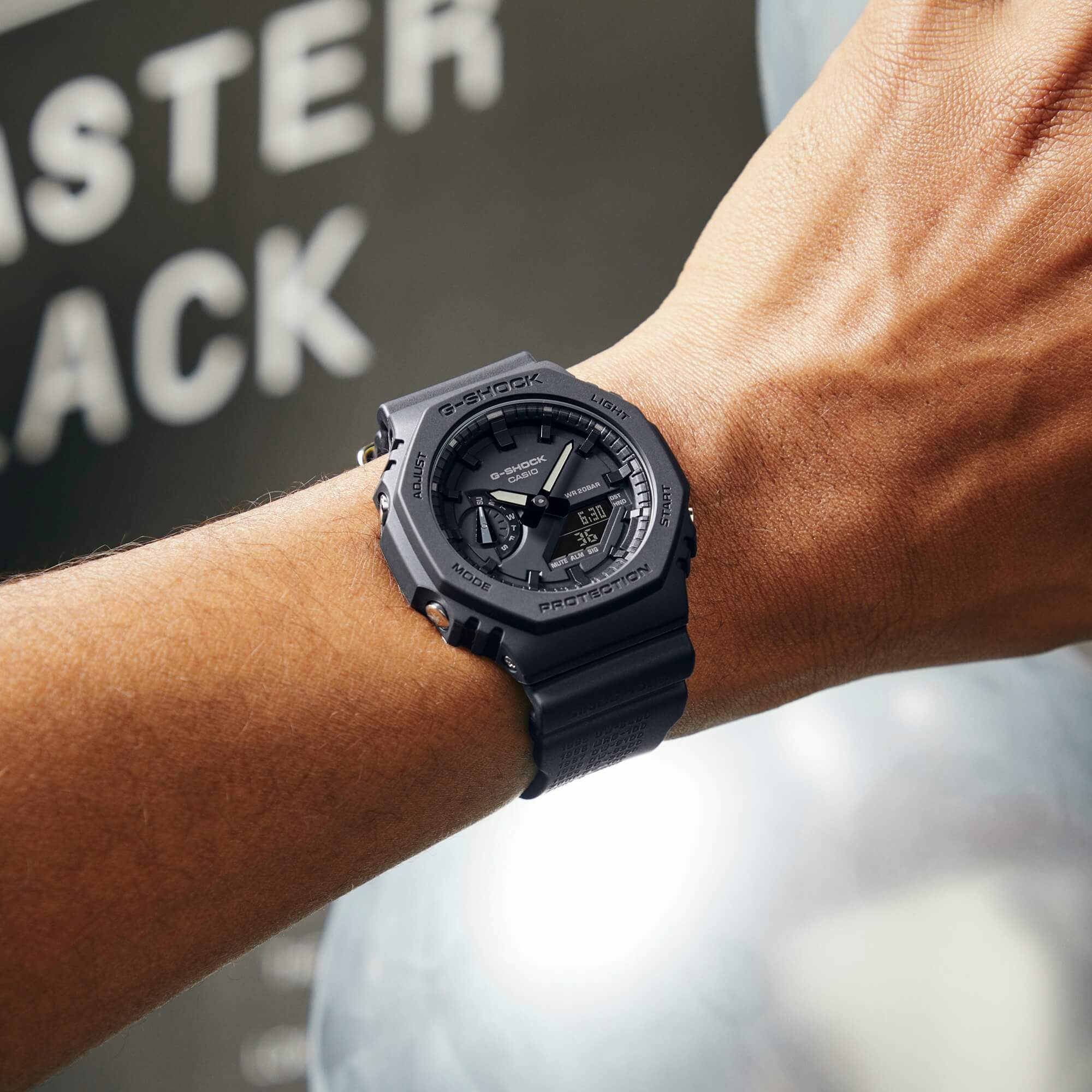 El reloj analógico «GA-2140RE-1A» completamente en negro, con correa de resina, pantalla analógica y caja octogonal en la muñeca de un hombre.