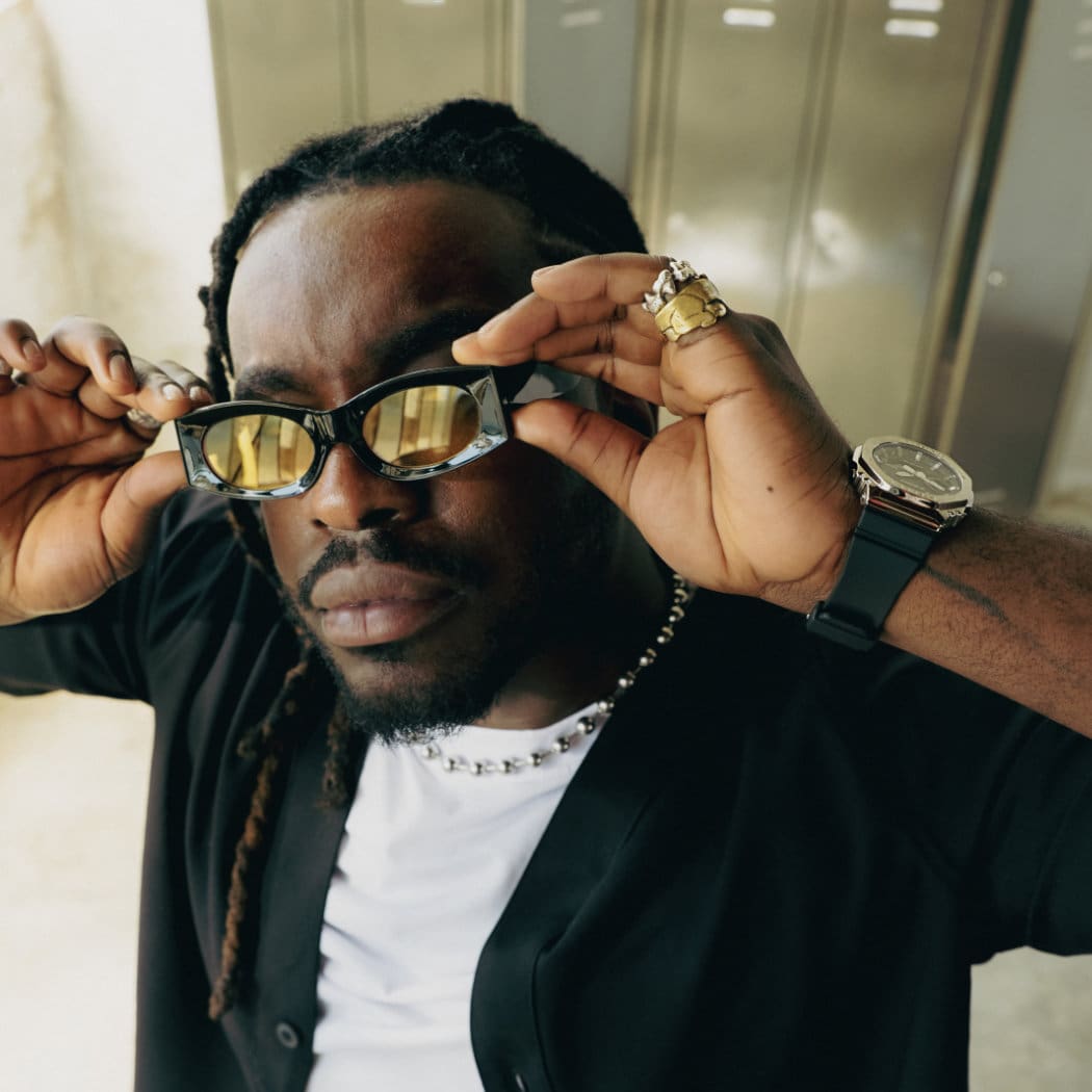 Un modelo masculino mira a la cámara con gafas de sol y joyas, además del reloj GBM-2100 de G-SHOCK