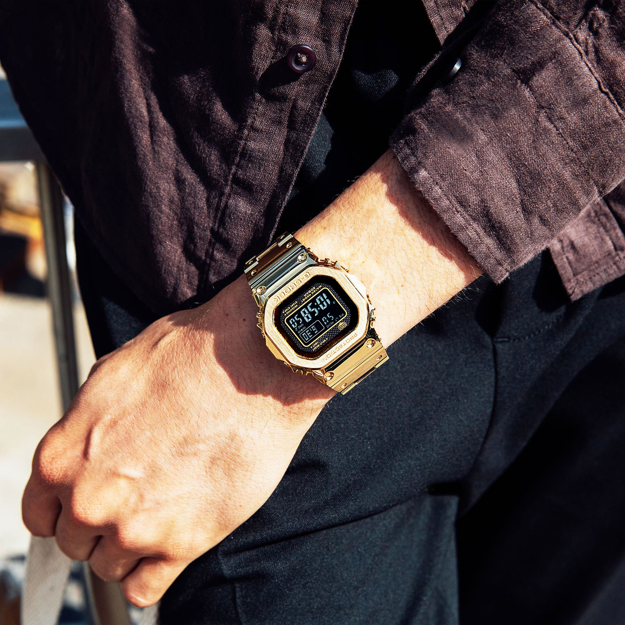 El reloj digital dorado GMW-B5000GD-9 con pantalla negra en la muñeca de un hombre