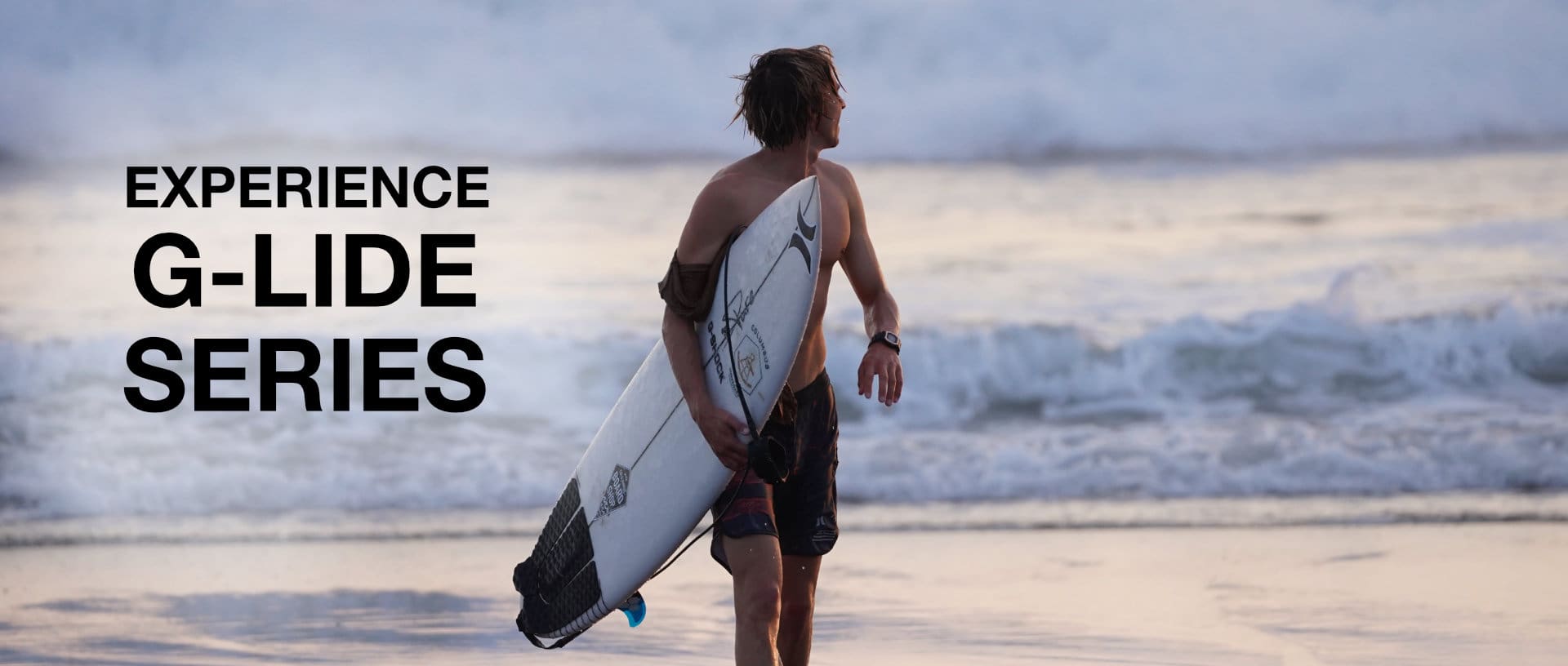 Un surfista en la playa lleva su tabla de surf; el texto complementa la imagen: Experience G-Lide