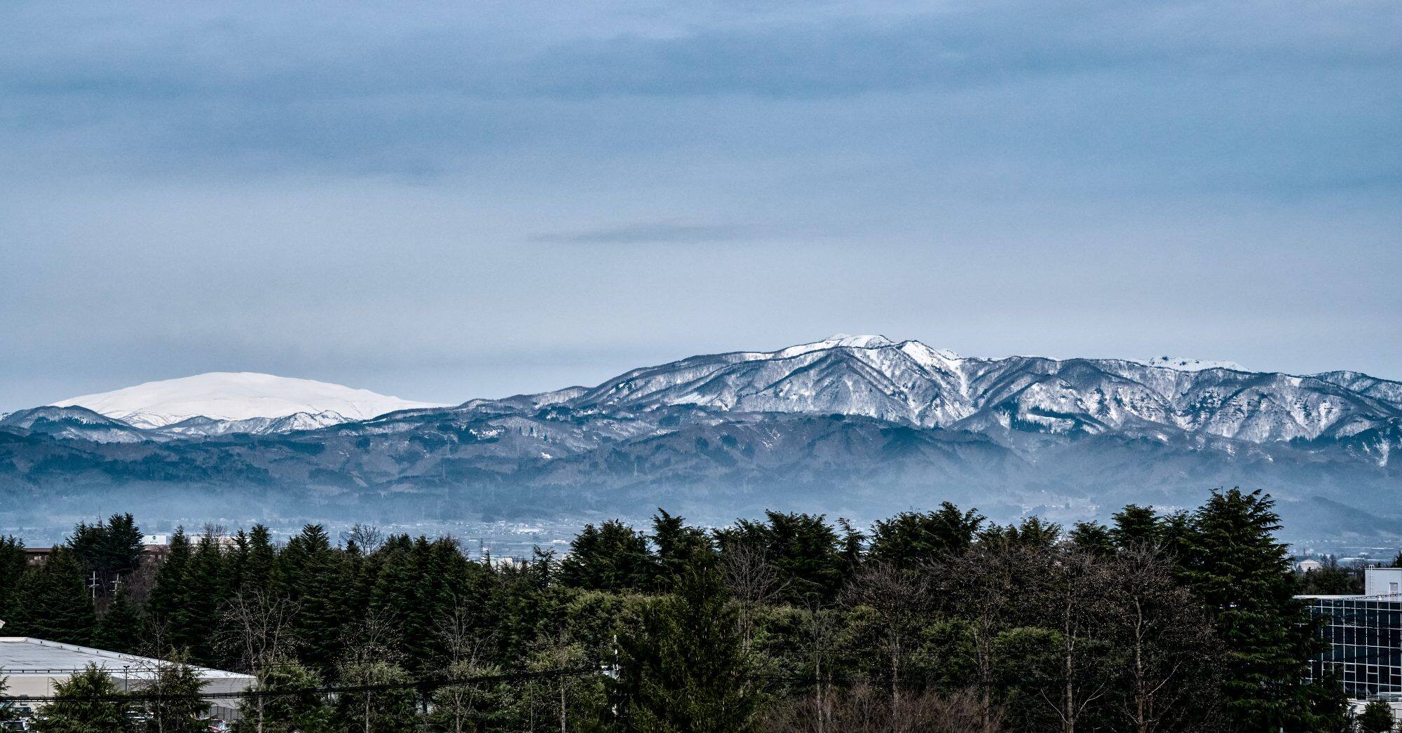 Vista de las montañas de Yamagata, Japón. En primer plano se ve una hilera de árboles.