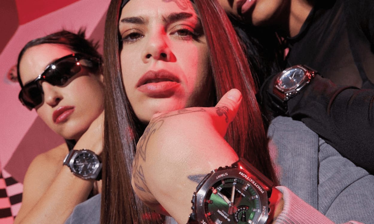 Tres mujeres en cuclillas en un pasillo cubierto de pintadas. En sus muñecas se ven los relojes G-SHOCK GM-2100.