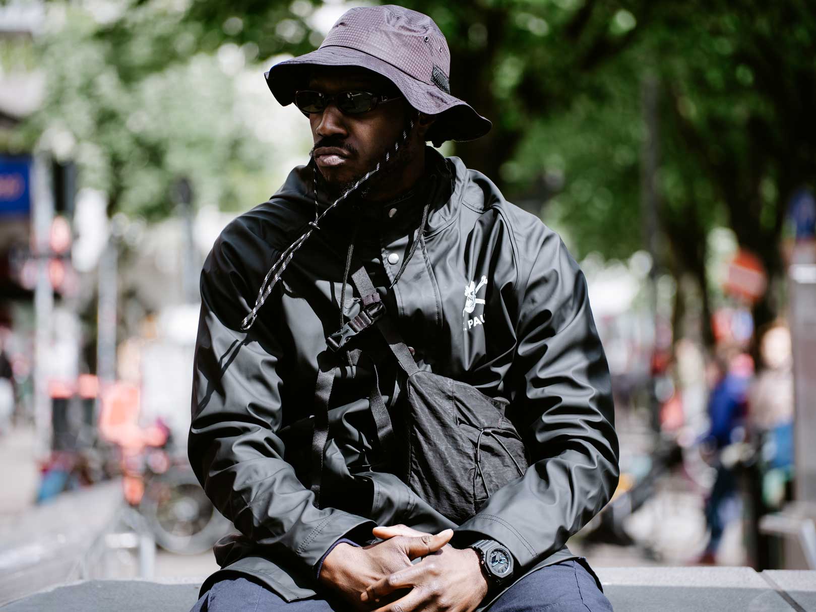 Rapper "Kwam.E" auf der Straße mit schwarzer Jacke, schwarzem Buckethat und schwarzer G-SHOCK Uhr