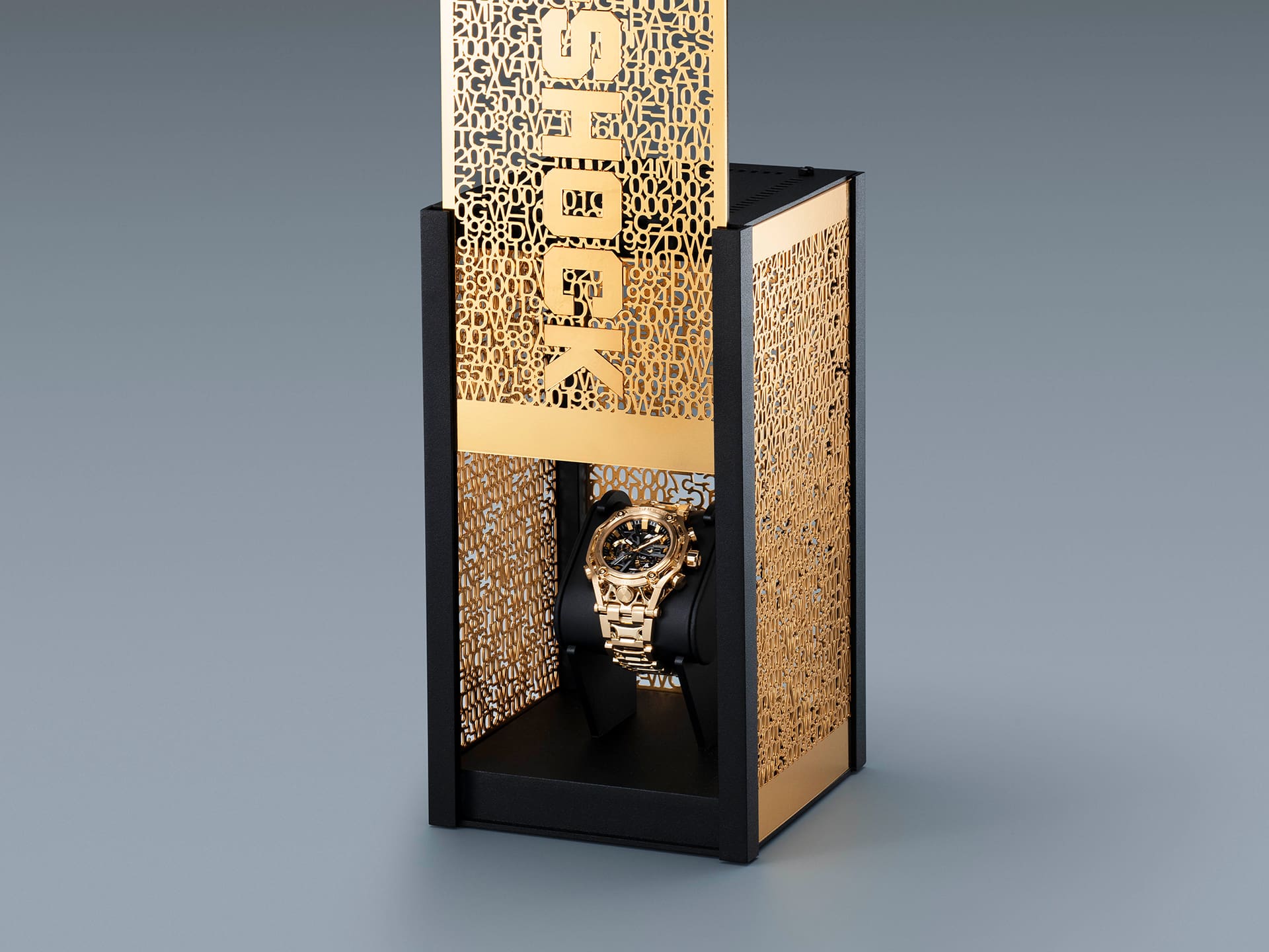 One side of the upright gold packaging is pushed up, concealing the G-SHOCK G-D001 wristwatch on a black roll.