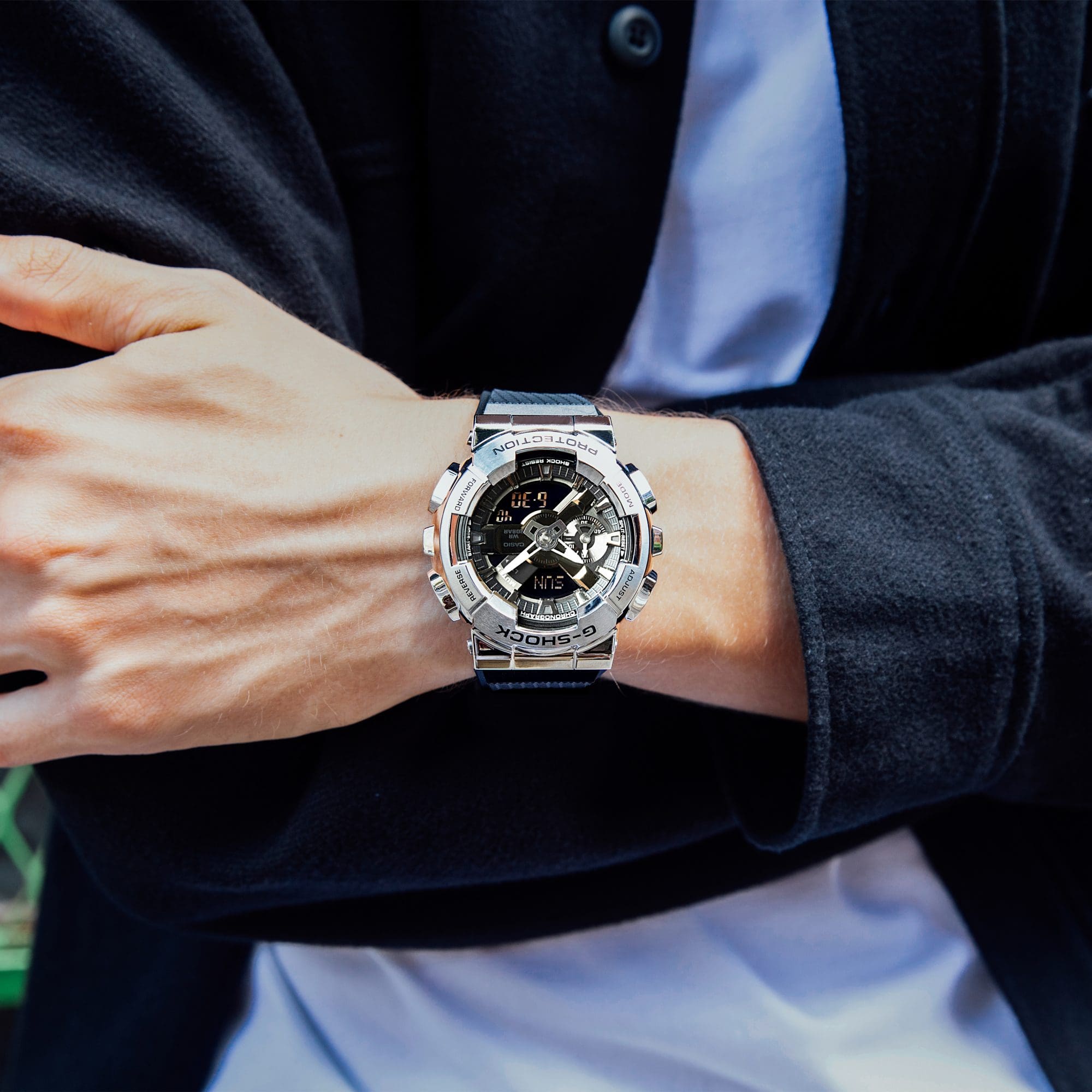 The silver colored wristwatch GM-110D with a big case worn by a man with a blue jacket