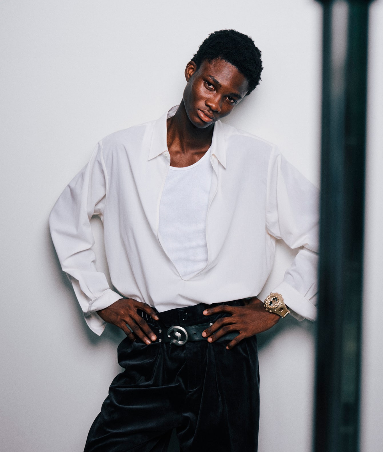 A model in black trousers and a white shirt wears the GA-V01A in gold on her wrist.