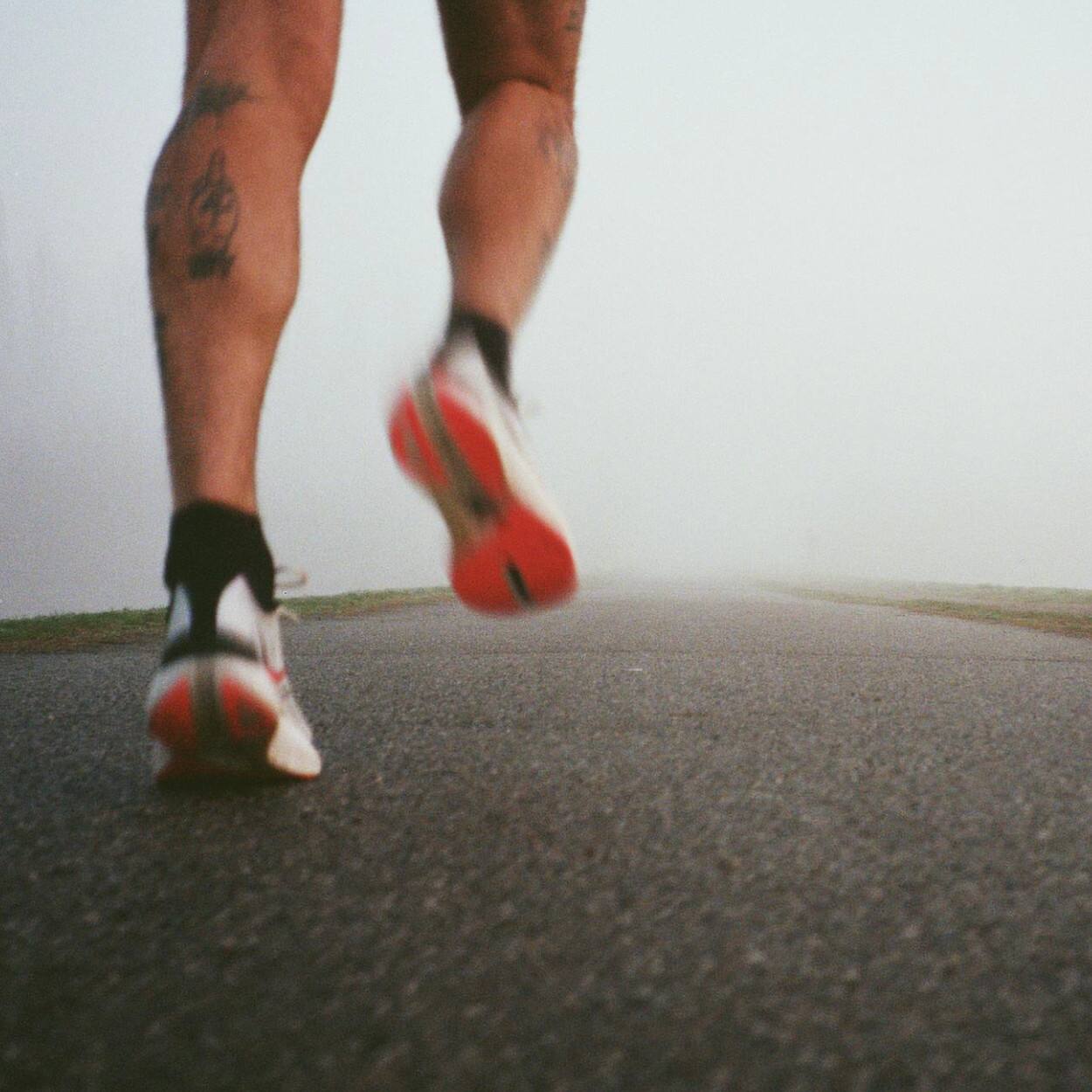 Gros plan sur les jambes d'une personne faisant son jogging sur l'asphalte.