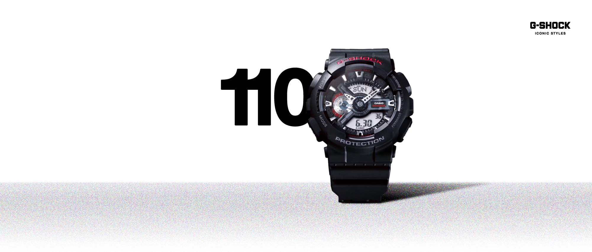 La montre analogique G-Shock 110 noire avec son grand boîtier sur lequel la date est affichée numériquement en arrière-plan de la lunette.