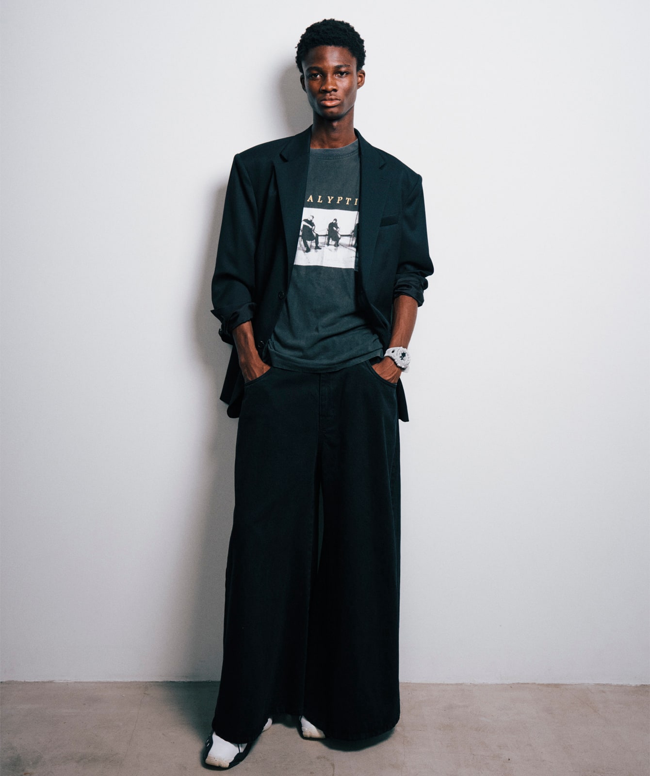 Un mannequin vêtu d'un pantalon noir et d'un blazer noir porte au poignet la grande montre-bracelet GA-V01 avec bracelet et boîtier blancs.