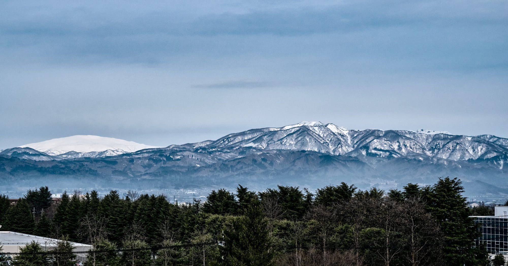 Vue sur les montagnes de Yamagata, Japon. Au premier plan, on peut voir une rangée d'arbres