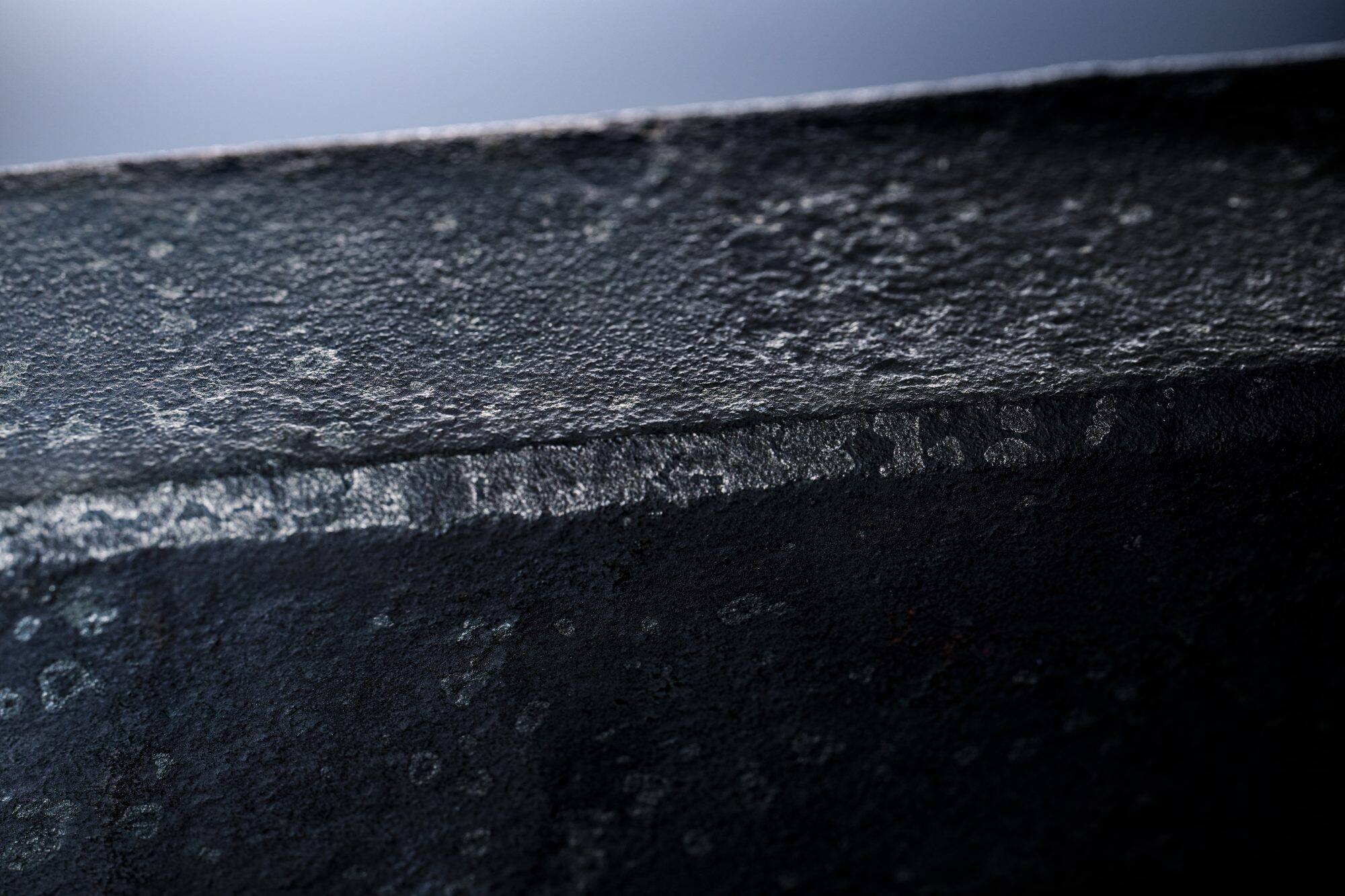 gros plan sur une surface métallique sombre et rugueuse avec une structure visible