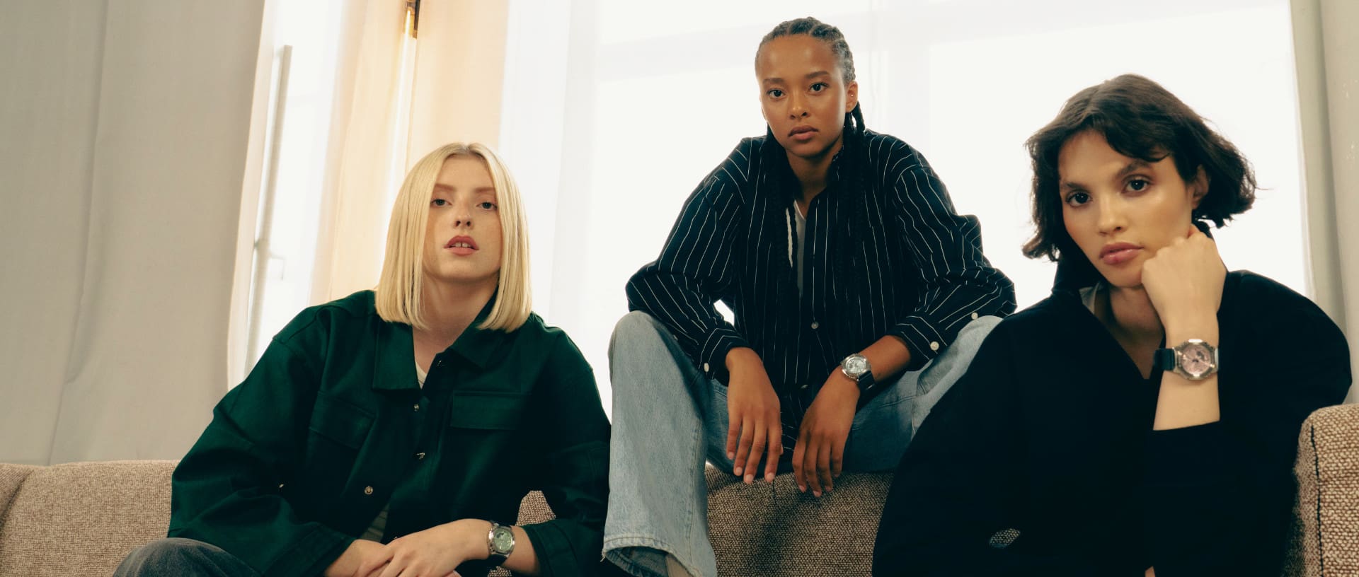 Trois femmes sont assises sur un canapé clair et portent des vêtements sombres. Les nouveaux modèles de montres GM-S2110 de G-SHOCK se distinguent au poignet.