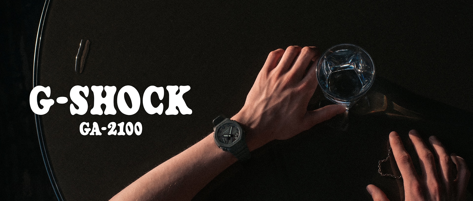 佩戴 G-SHOCK GA-2100 腕錶的男子拿著玻璃杯。
