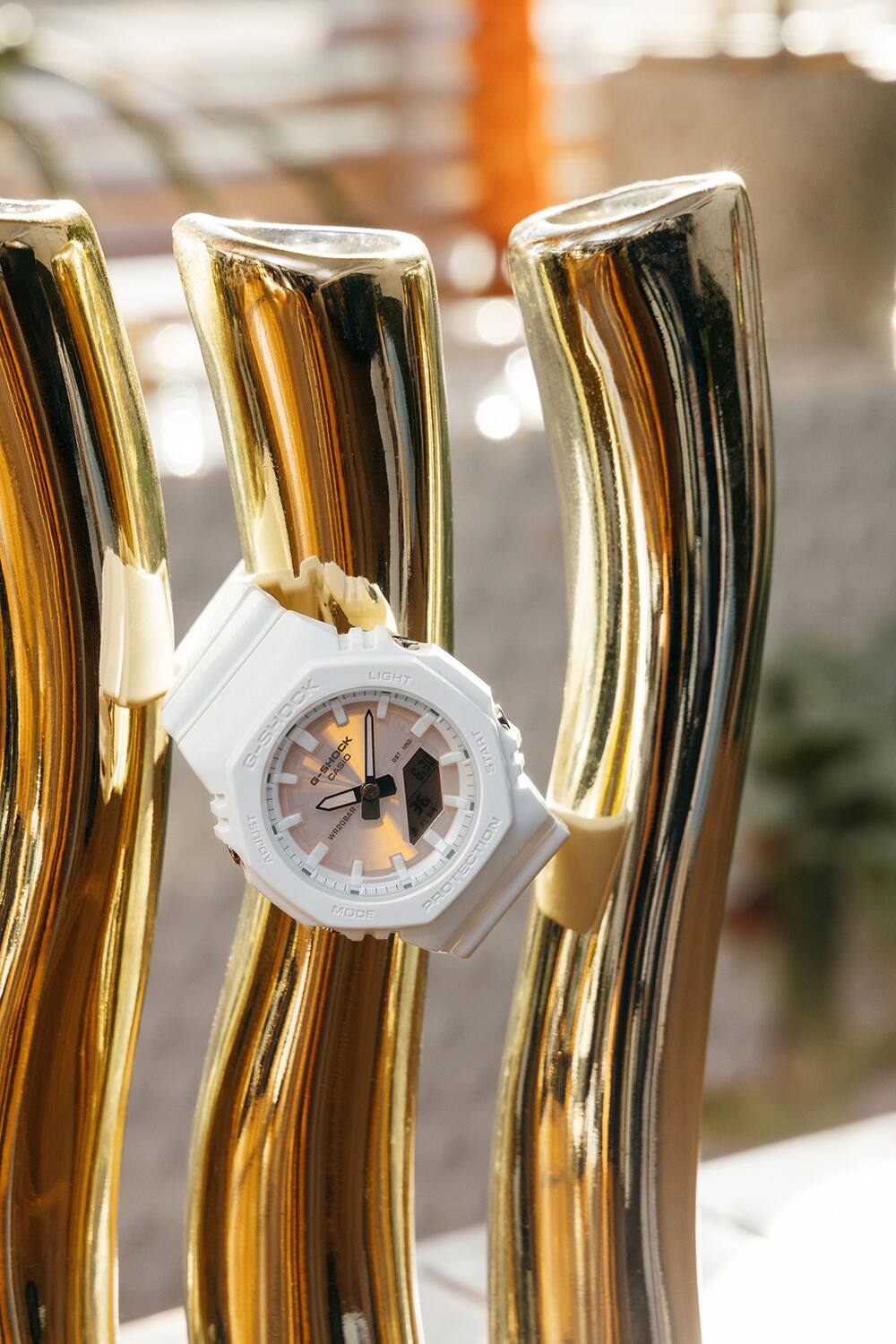 金色物件與 G-SHOCK GMA-P2100PC-7A 腕錶的照片