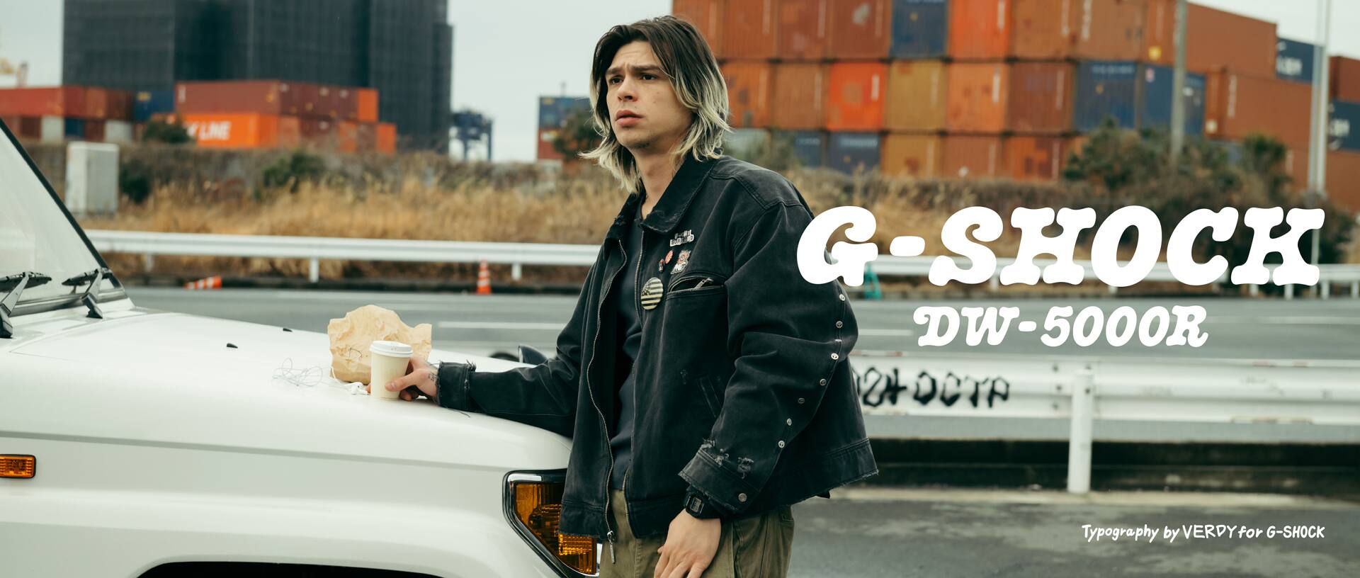 Person standing by a car in an industrial port wearing G-SHOCK DW-5600R.