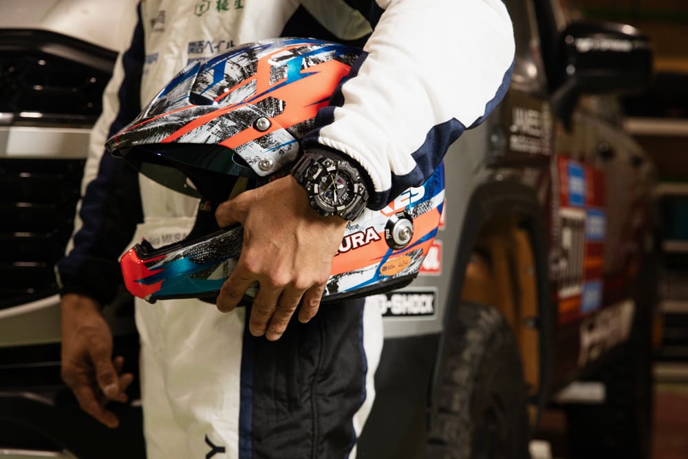Miura Akira grabs his helmet with his left hand wearing the G-SHOCK GWG-B1000TLC.