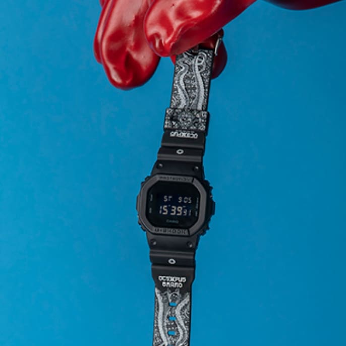 L'orologio davanti a uno sfondo blu sorretto da un guanto rosso