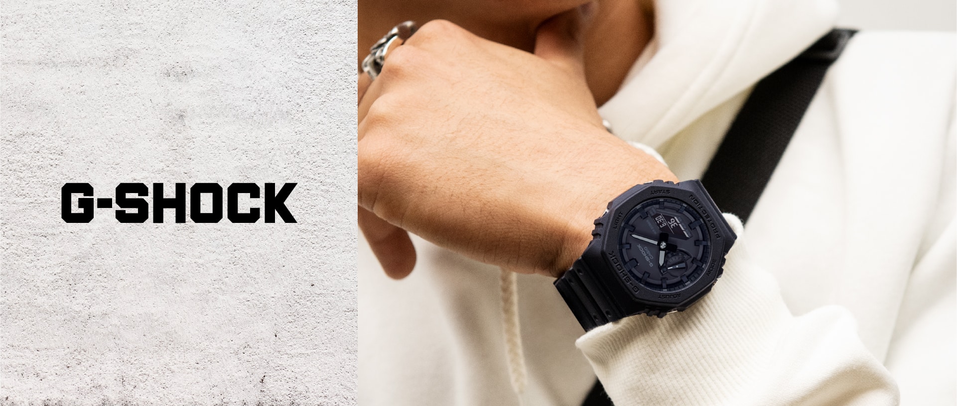 L'orologio da polso GA-2100 nero di G-SHOCK con display analogico al polso di una persona con una felpa bianca.