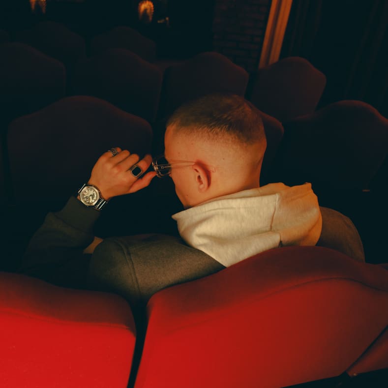 Un uomo indossa il GM-2100YM-8ER di G-SHOCK e siede in un cinema buio.