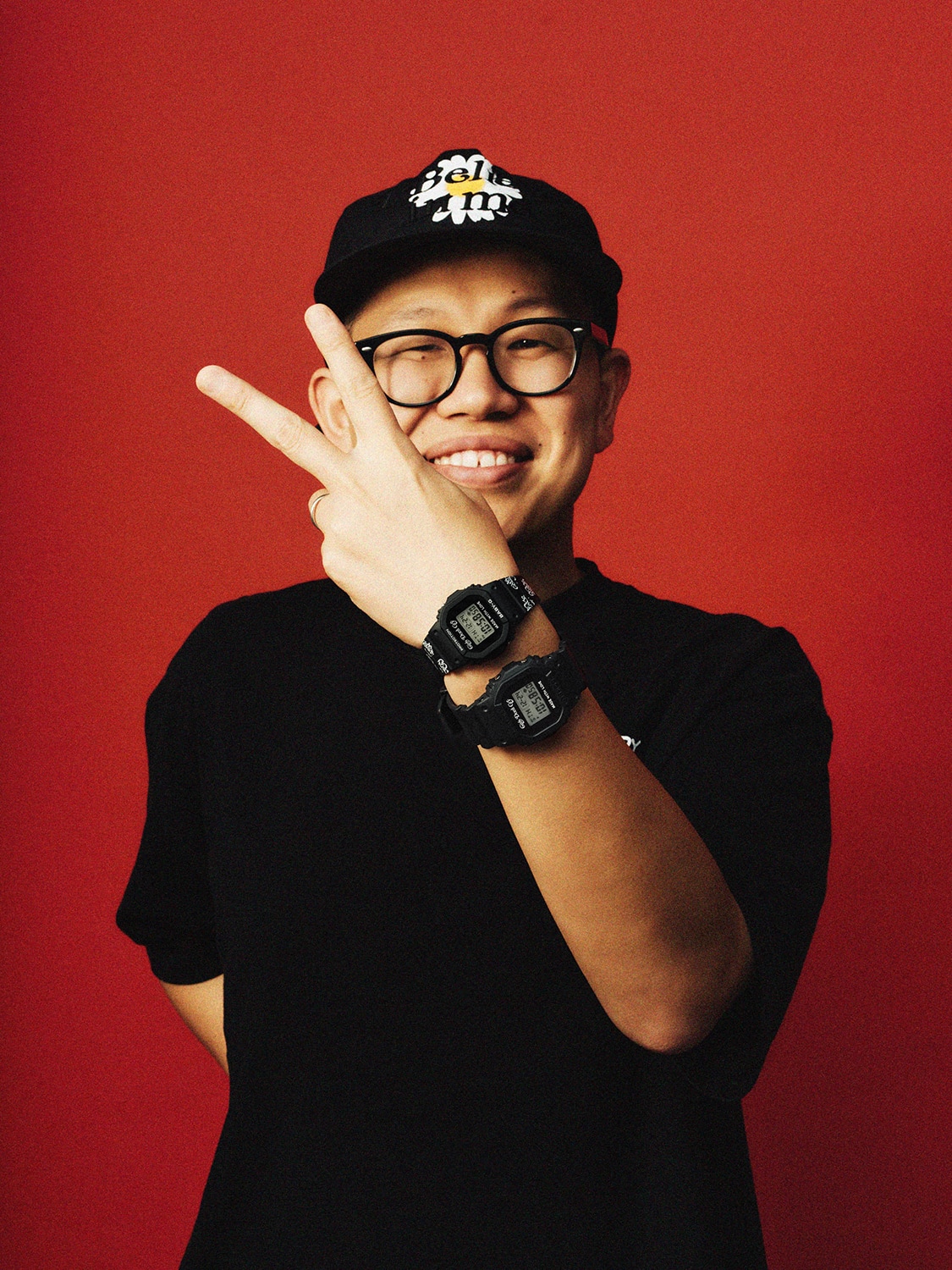VERDY가 블랙 G-SHOCK 시계를 착용하고 레드 배경에서 포즈를 취한 사진