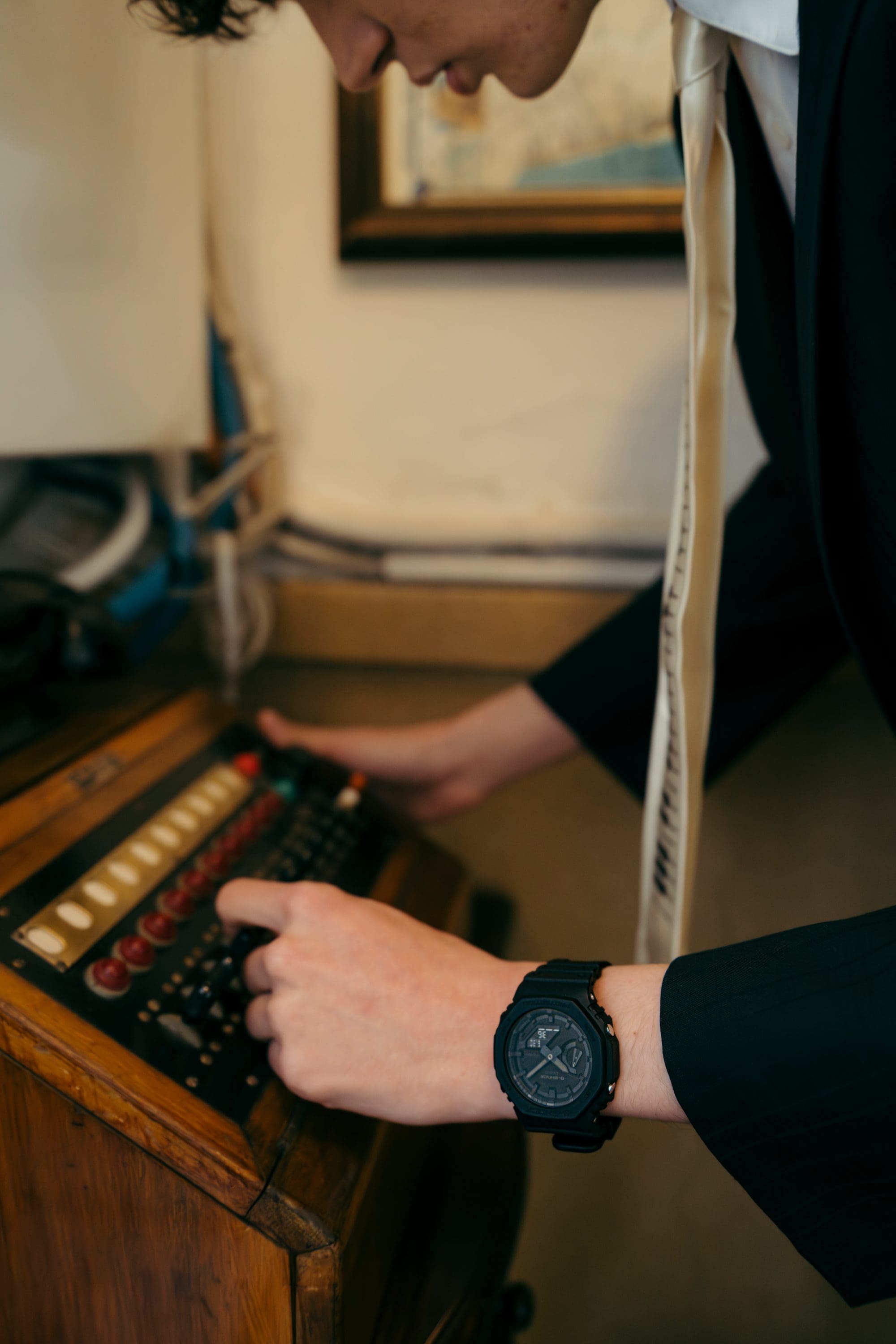 Person interacting with vintage furniture wearing G-SHOCK GA-2100 indoors.