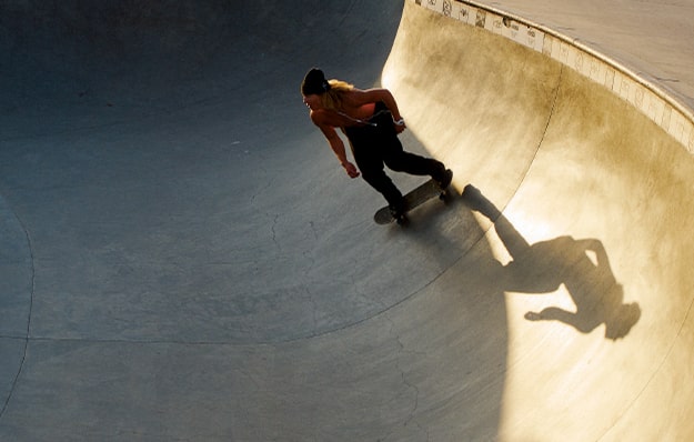 Skateboarder patinando en un skatepark al atardecer.