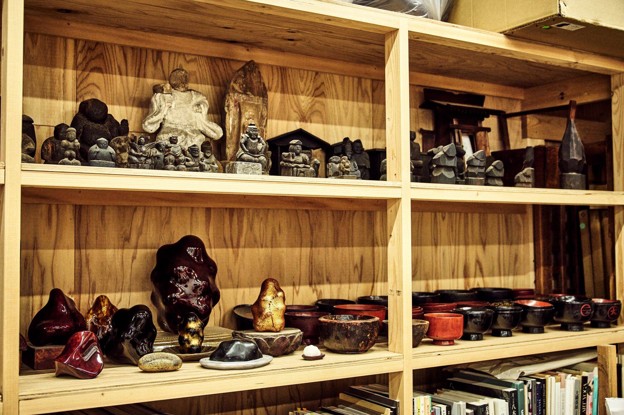 Lacquerware, folk buddhist statues, and other handcrafted items line the shelves in Ishizuka’s studio.