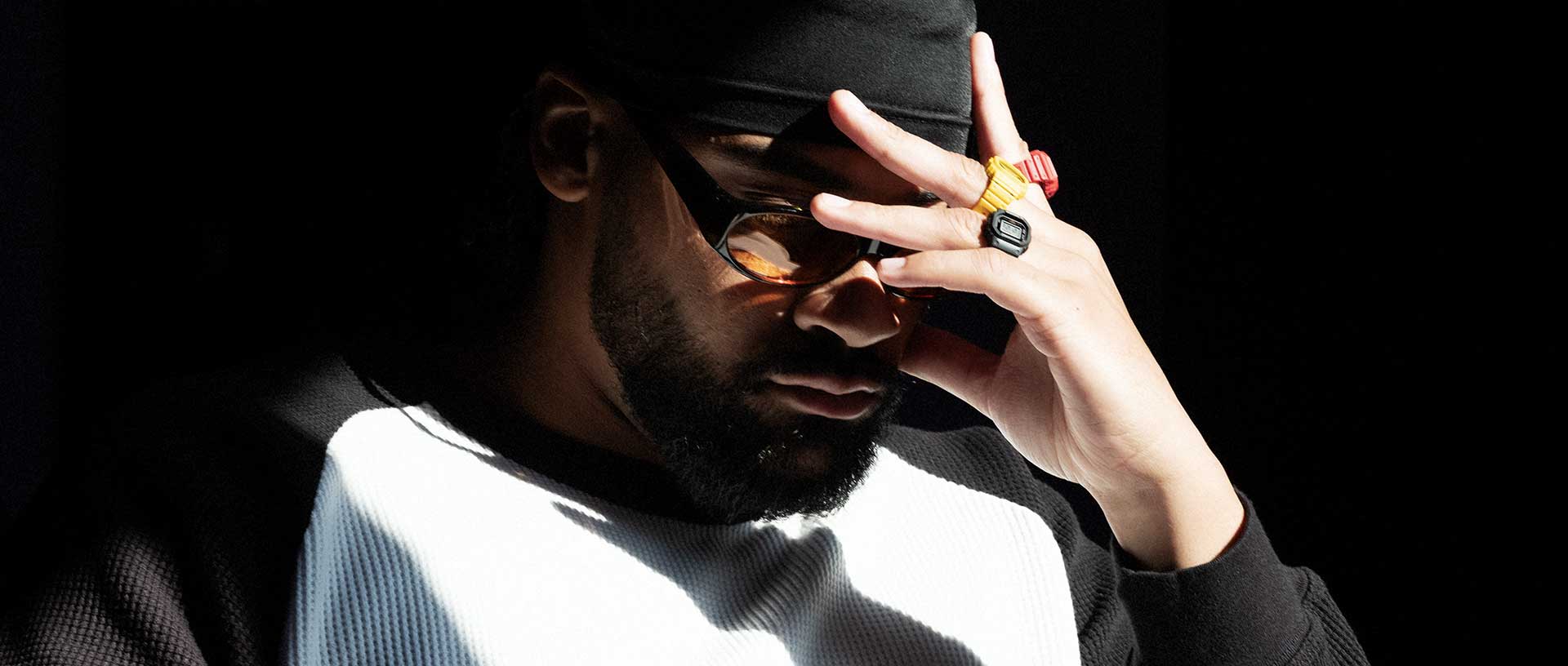 Um homem protege os olhos do sol e usa as três variações de cor do relógio de anel DWN-5600.