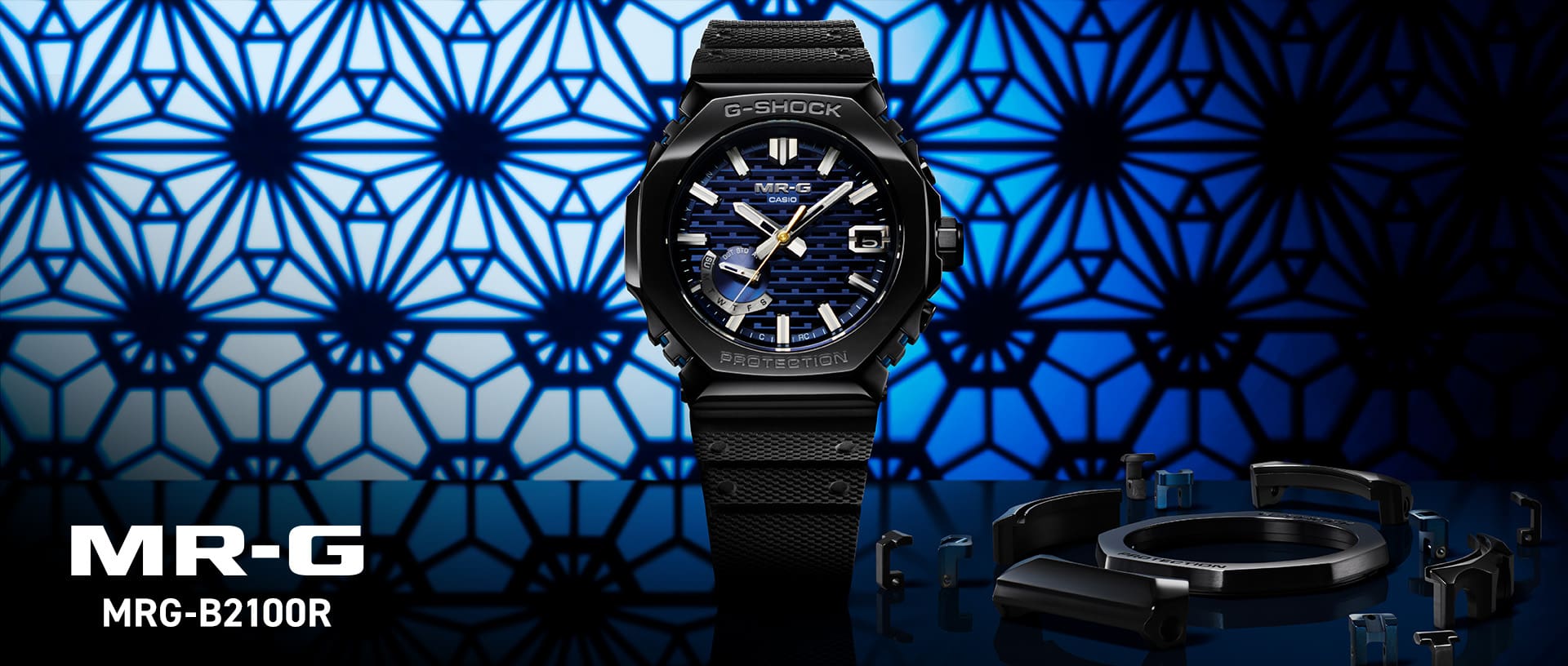 Relógio de pulso G-SHOCK “MRG-B2100R” com caixa preta, bracelete Dura Soft e luneta azul em frente a um fundo patinado a preto e azul