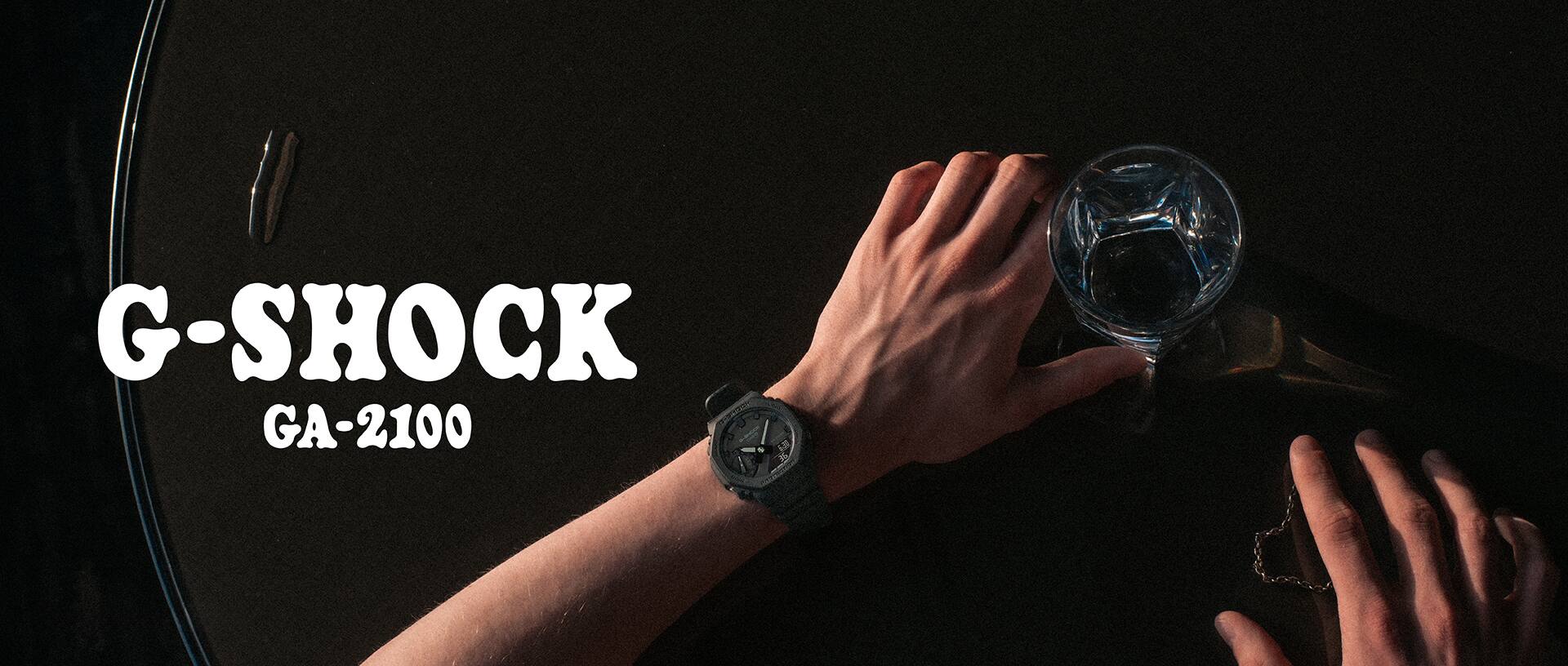G-SHOCK GA-2100 saati takan bir adam elinde bardak tutuyor.